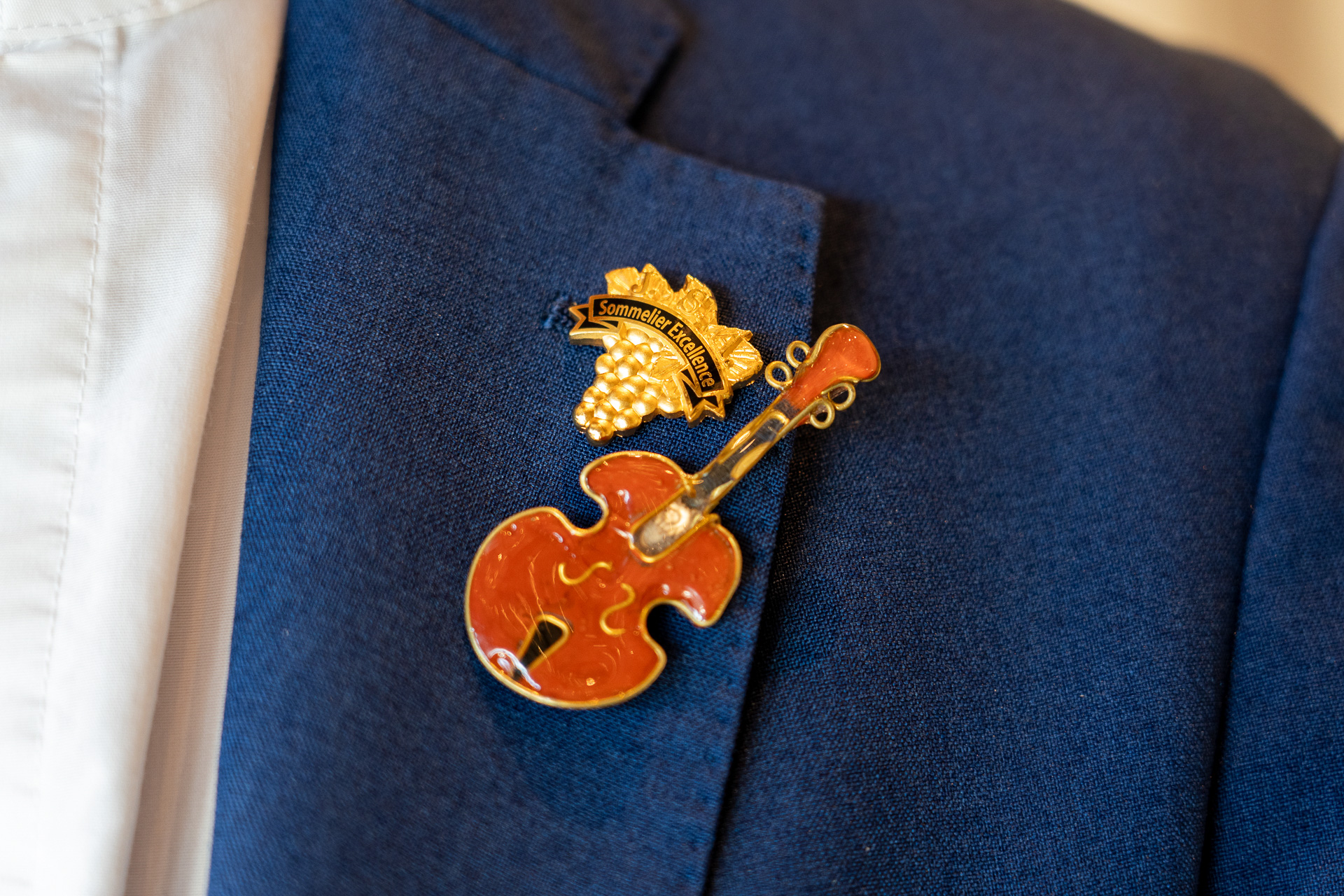 「ソムリエ・エクセレンス」バッジの横に付いていたのはギターの絵柄のピンバッジ。音楽が得意分野のスタッフさんです