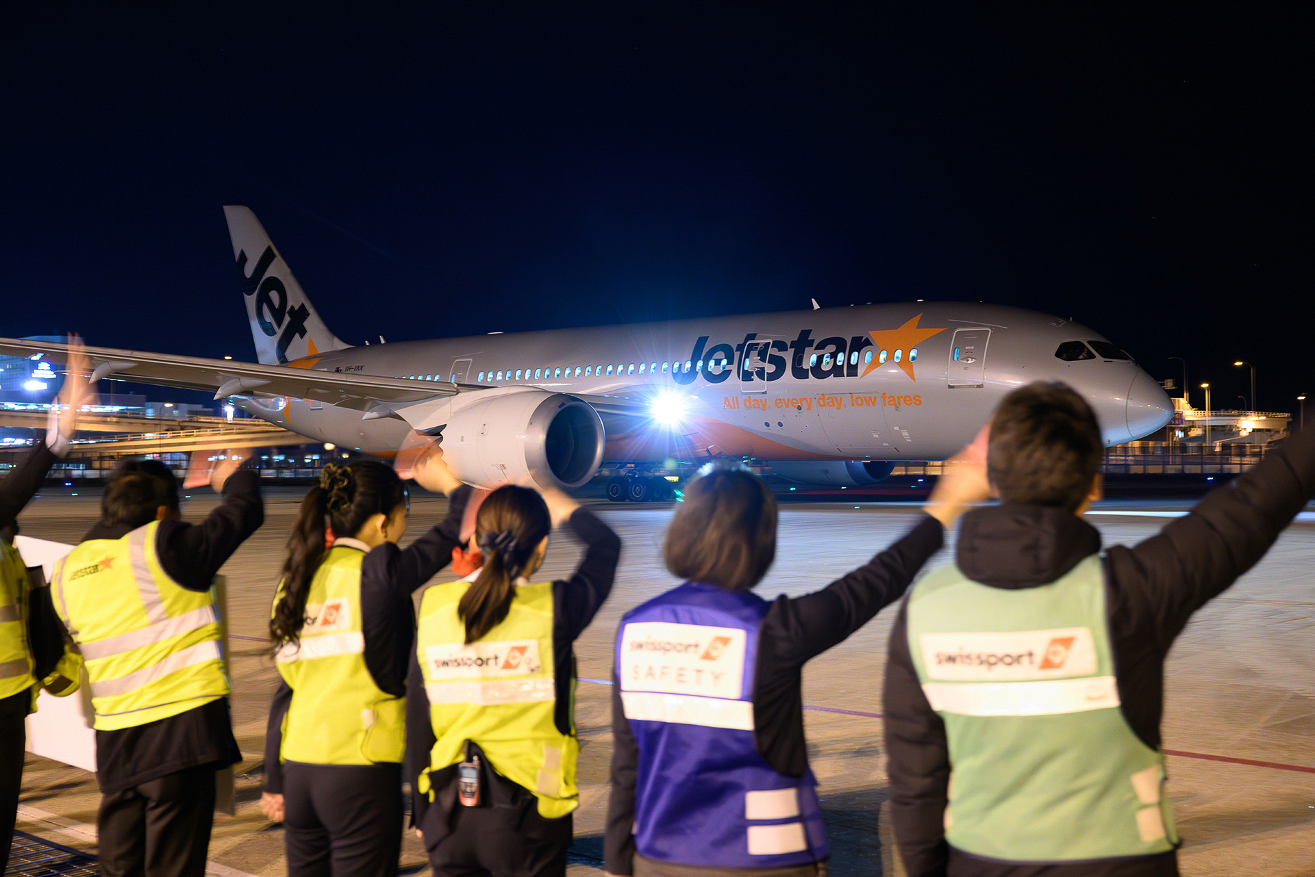 プッシュバックされるボーイング 787-8（登録記号：VH-VKK）に手を振って見送るジェットスター、関西エアポート、スイスポートジャパンの職員