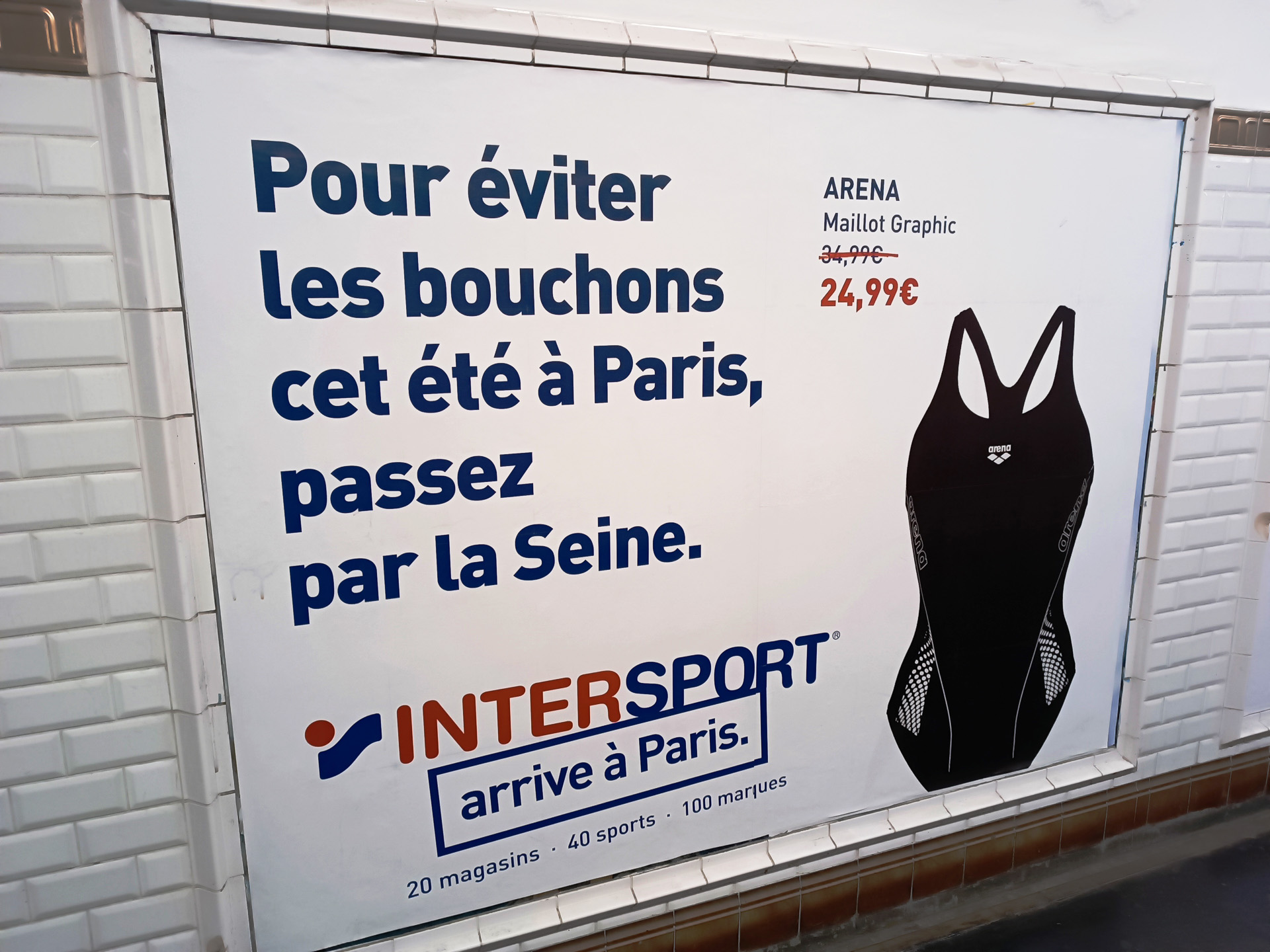 「この夏の混雑を避けるために、セーヌ川で泳ごう」と書かれたスポーツ専門店の広告