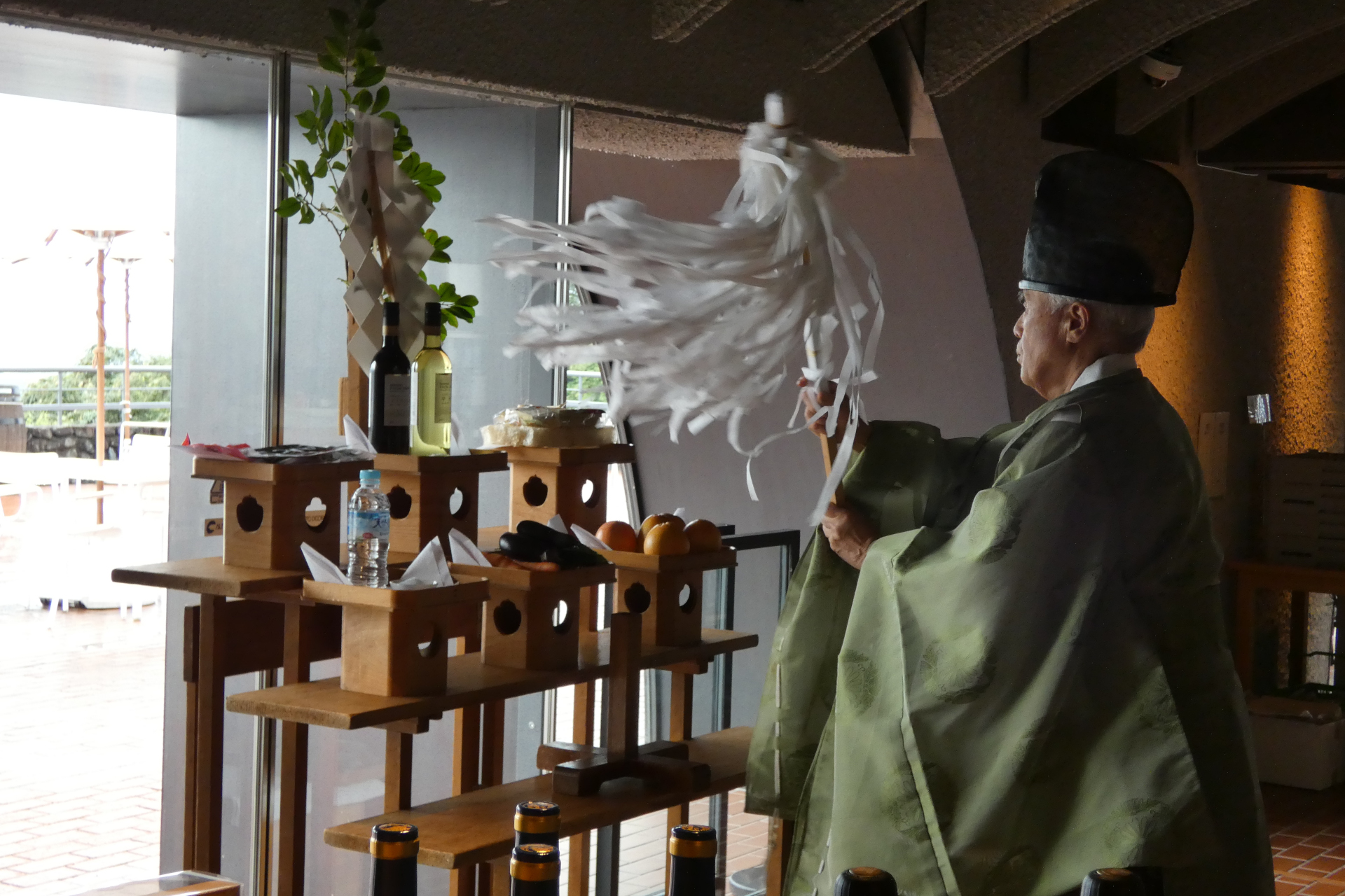 雨天のため「収穫始め式」は屋内で行なわれた。ワイナリーだけに御神酒がワインになっている