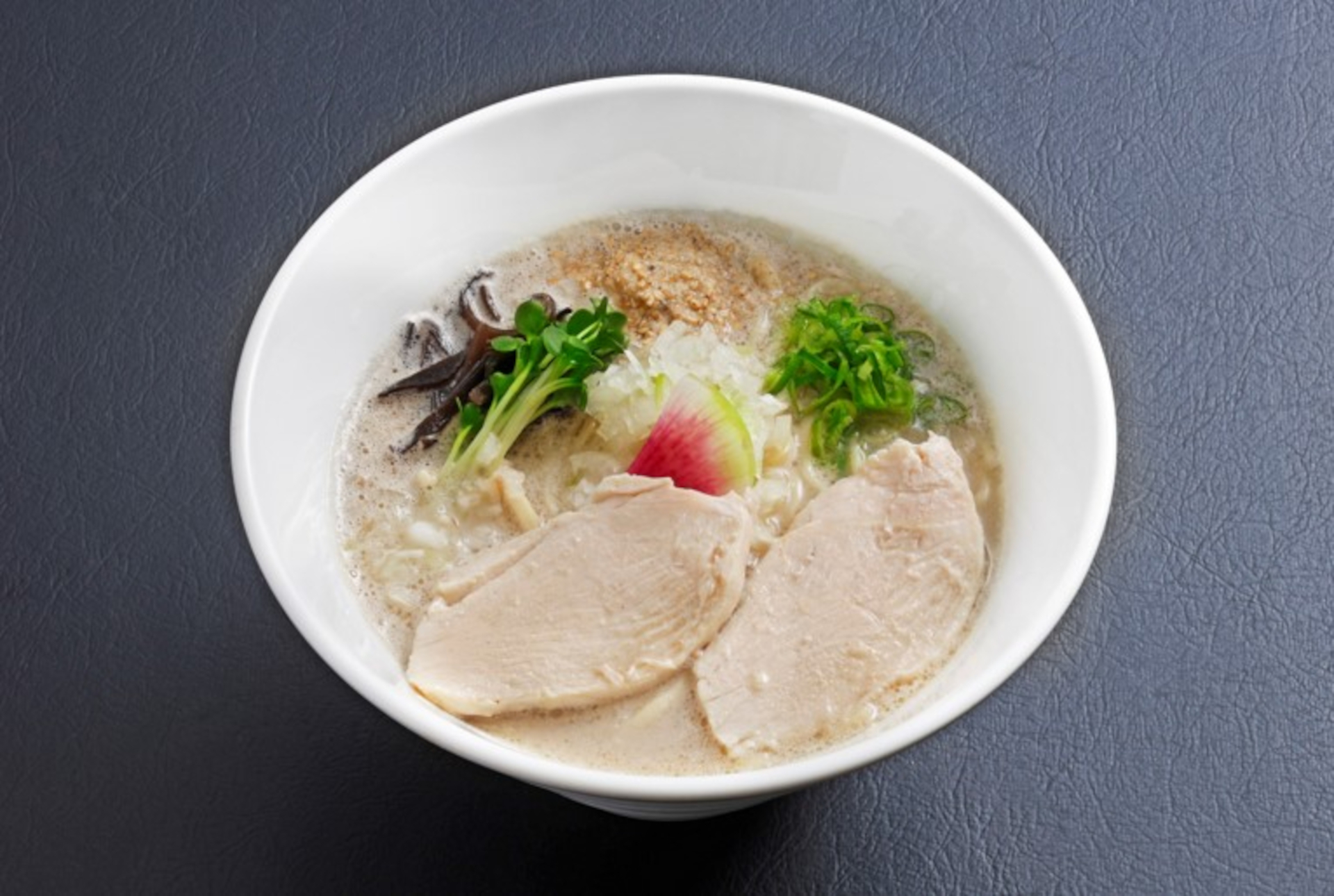 牛骨スープと関西風の和出汁を融合したらーめん 牛骨の王。焦がしニンニクオイル入り「BLACK黒王」や特製スパイス入り「SPICY赤王」などのメニューも