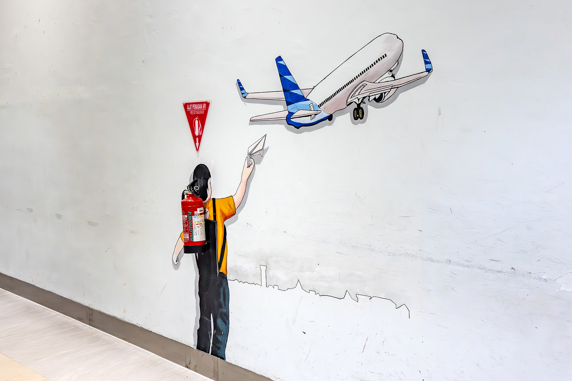 謎アートが描かれた消火器。機体がガルーダ・インドネシア航空カラーなのが芸コマ