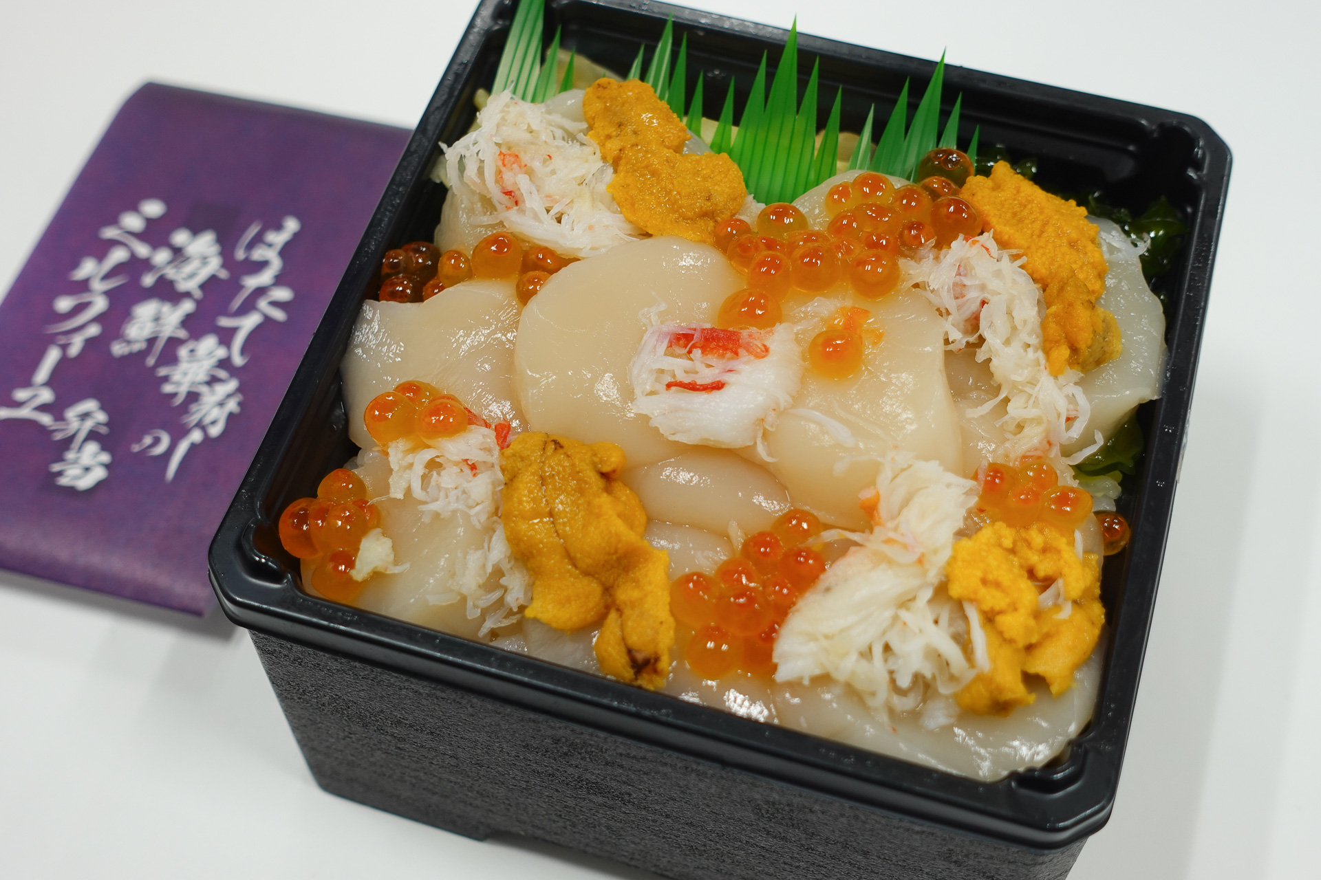 「ほたて華寿しの海鮮ミルフィーユ弁当」。6層は（下から）→酢飯→サーモンフレーク・サーモン切り身・ししゃも卵→酢飯→鮪のたたき大葉入り→酢飯→ホタテ・ウニ・イクラ・カニ