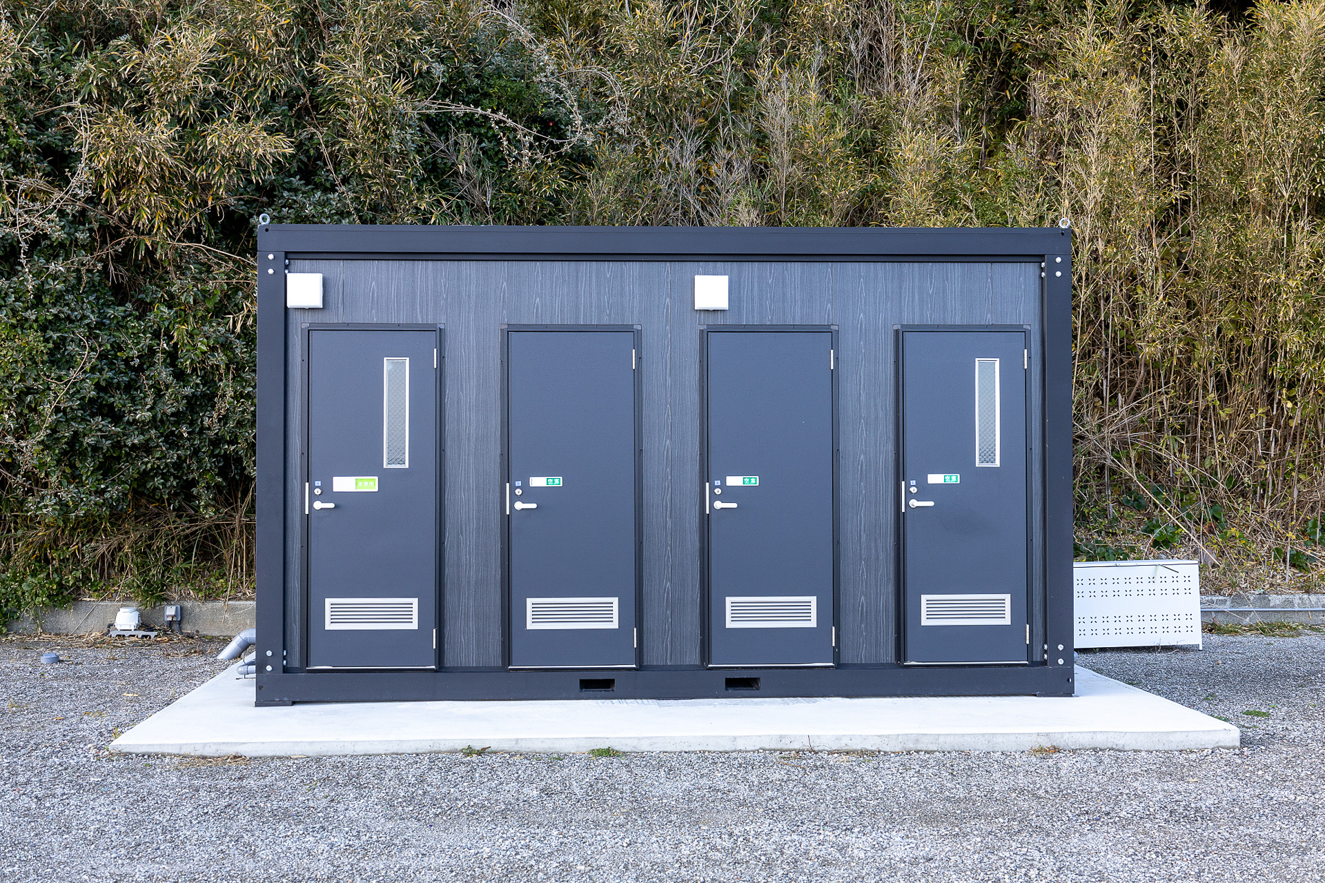 シャワーとトイレがある建屋。ドアに細長い窓があるのがトイレ。窓がないのがシャワー室