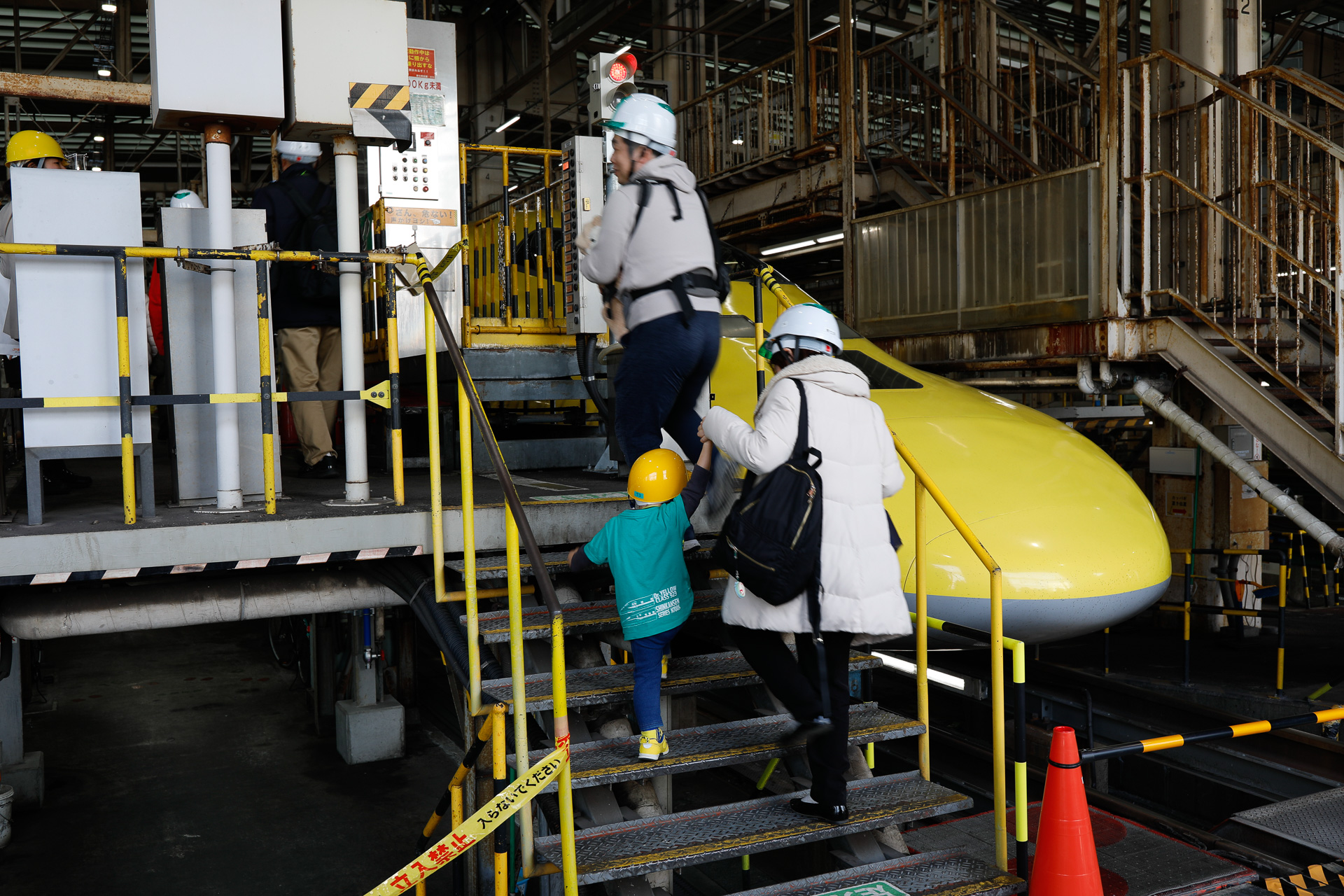 検修庫にやってきた参加者が、作業台に登る。作業台は車両の客室床面と同じ高さで、車内整備や車内設備の検修に使われる。左下に、地平より低いレベルのスペースが見えるが、これは台車や床下機器の検修を実施するためのもの