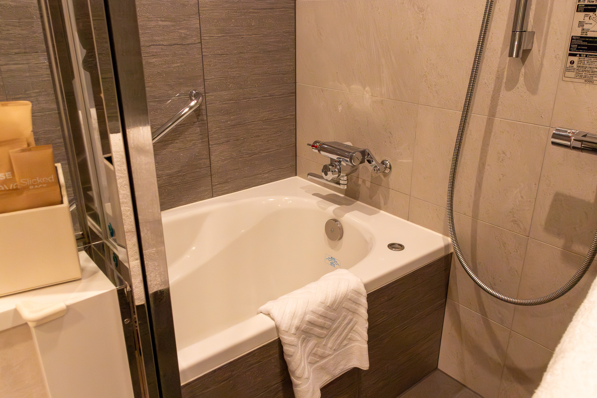 広めのバスタブ。洗面台とはガラス戸で仕切られている