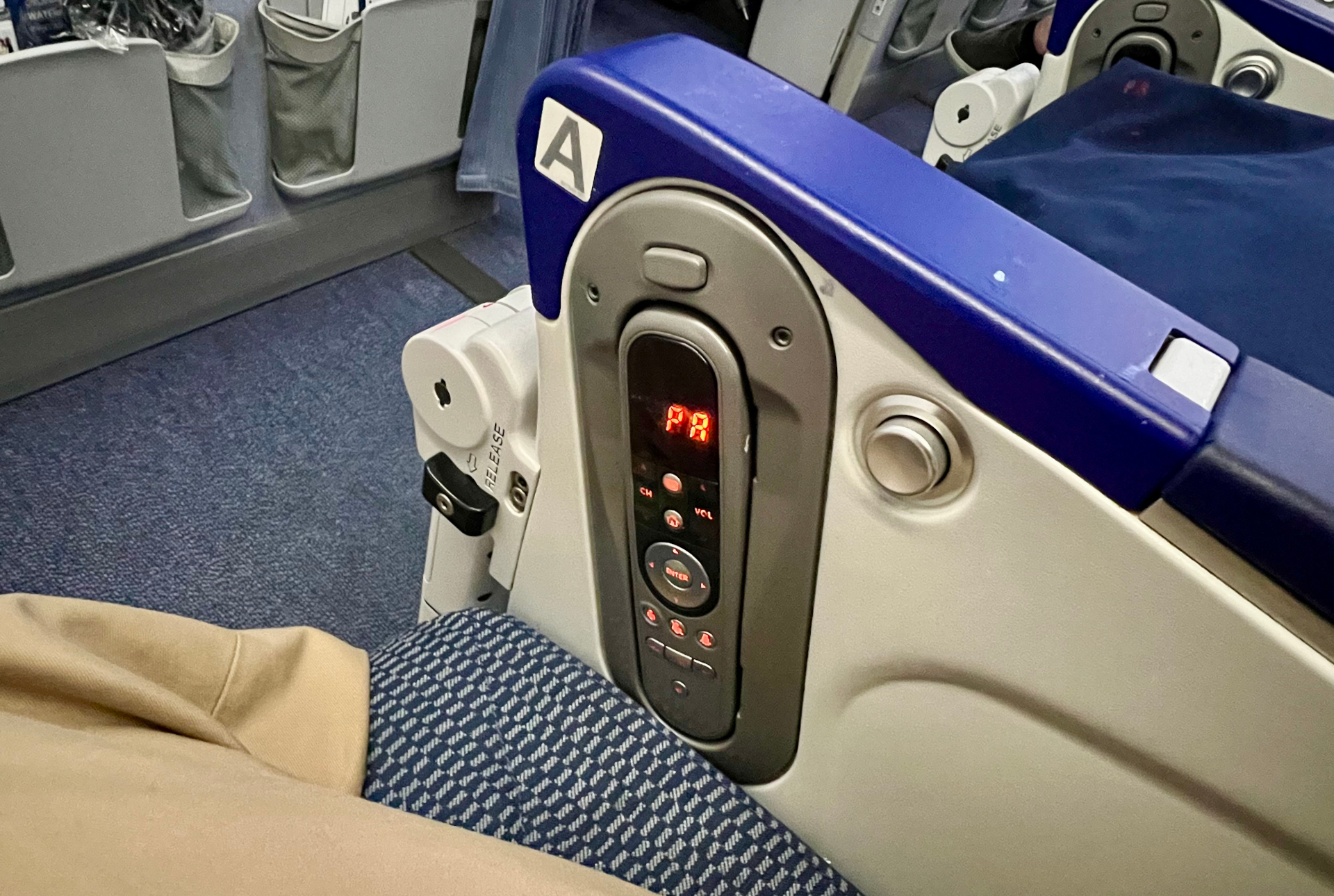 バルクヘッド席の個人モニターと食事テーブルは、アームレスト部分に格納されている。目の前の壁には機内安全ビデオやフライトマップが流れるモニターと個人専用収納ポケット