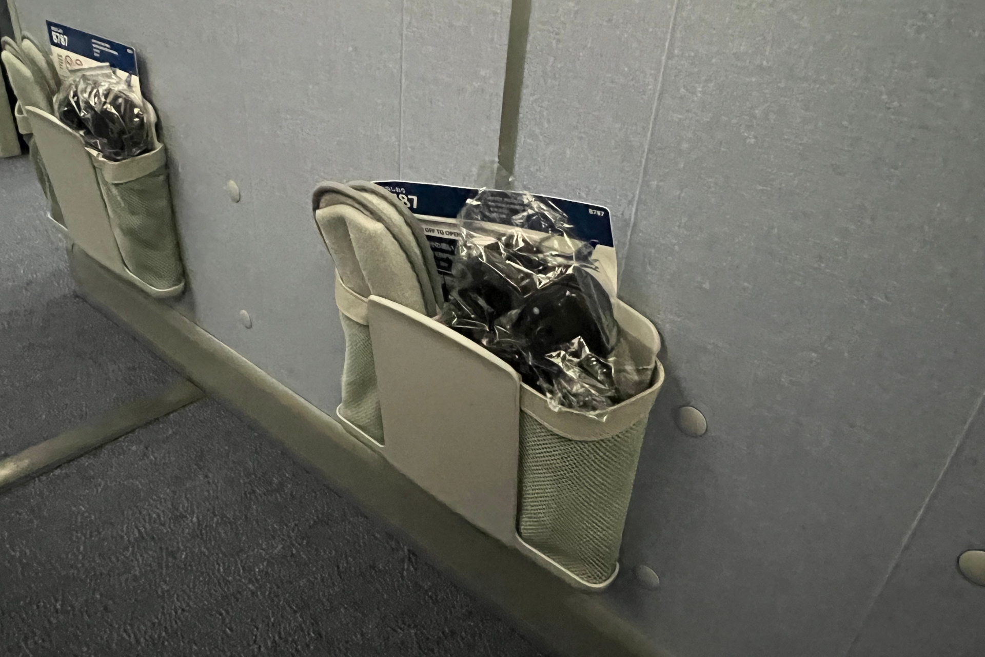 バルクヘッド席の個人モニターと食事テーブルは、アームレスト部分に格納されている。目の前の壁には機内安全ビデオやフライトマップが流れるモニターと個人専用収納ポケット