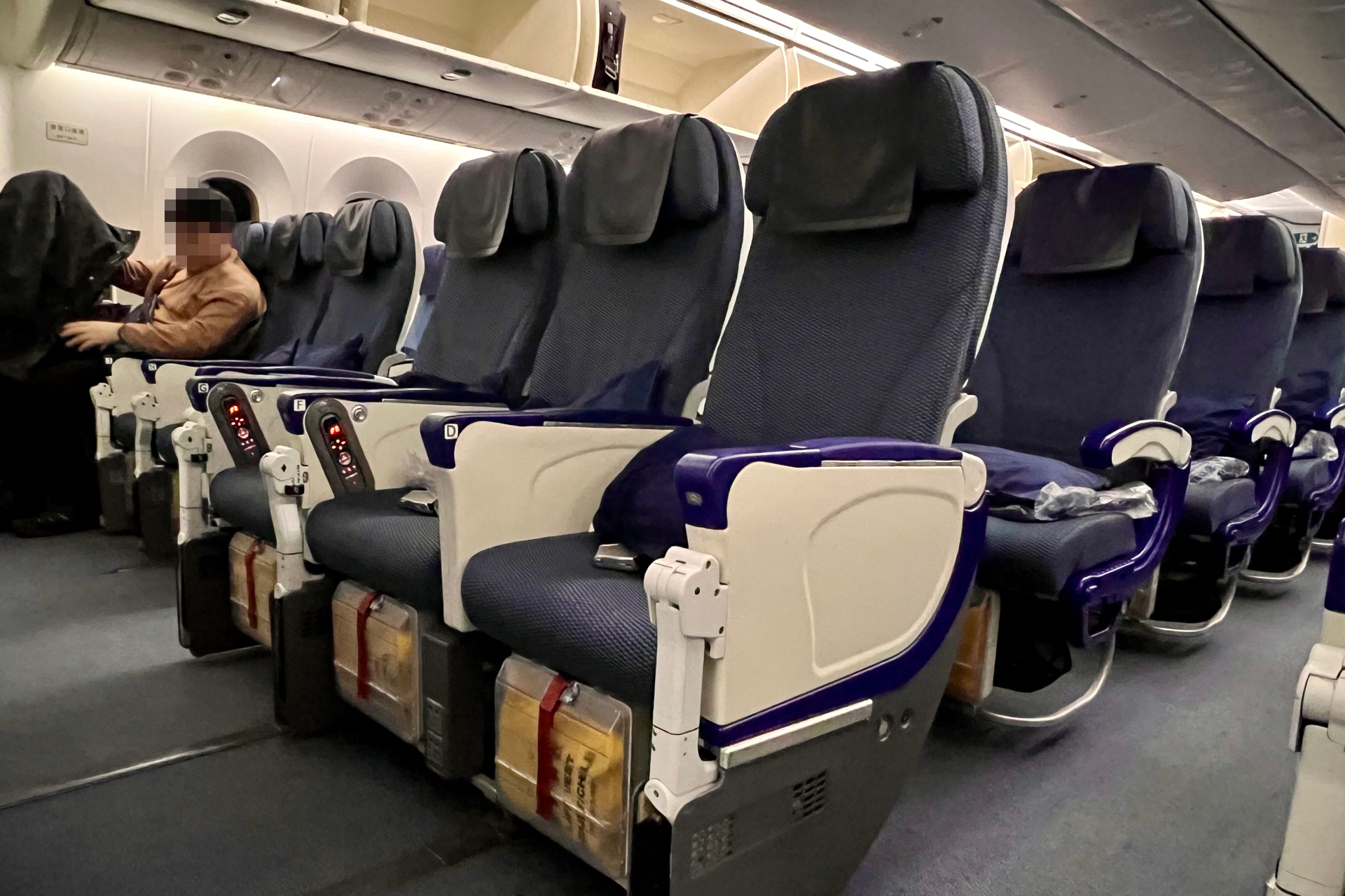 バルクヘッド席・非常口席は隣席同士のアームレストが上がらず、フットレストもない（通常席には写真右のようにネットタイプのフットレストが備わる）