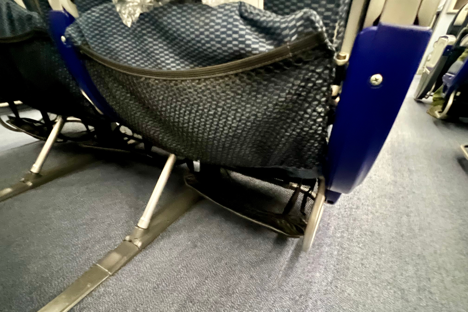 バルクヘッド席・非常口席は隣席同士のアームレストが上がらず、フットレストもない（通常席には写真右のようにネットタイプのフットレストが備わる）