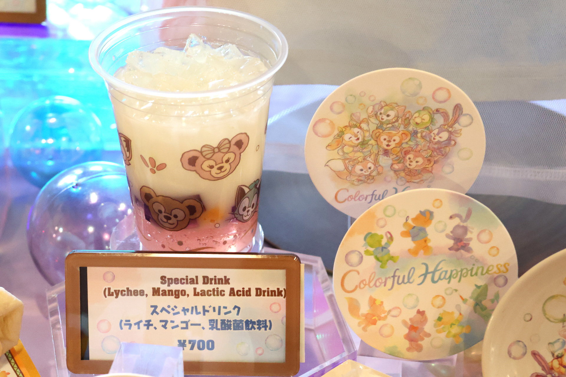 「スペシャルドリンク（ライチー、マンゴー、乳酸菌飲料）」には（700円）紙製のカラフルハピネスのコースターが付属。＋1500円でスーベニアタンブラーも付けられる