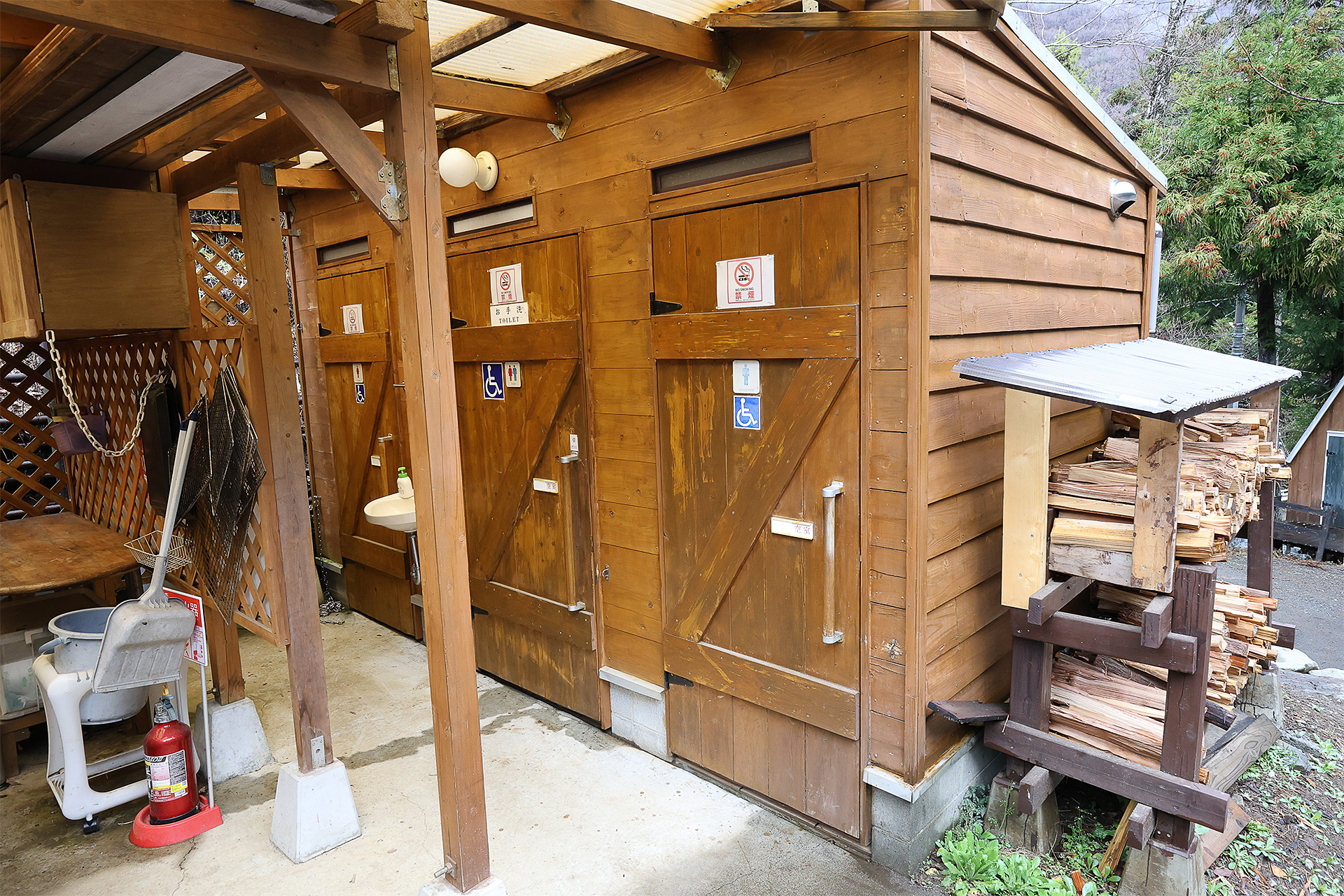 炊事場の横がトイレ棟。女性用1つ、男女兼用が1つ、男性用が1つの計3つ。入口には屋根と照明もある。トイレは個室内も建屋自体も清潔な印象