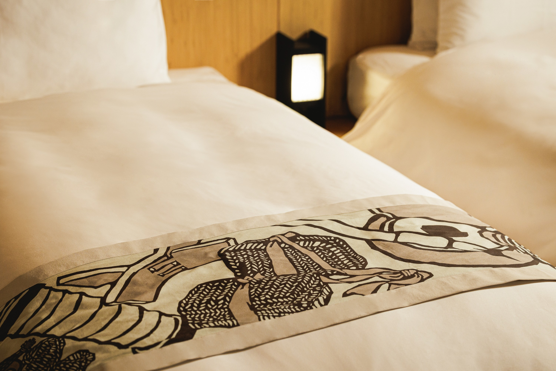 旅人が宿で広げる旅道具を壁面のアートやベッドスローのデザインに取り入れた