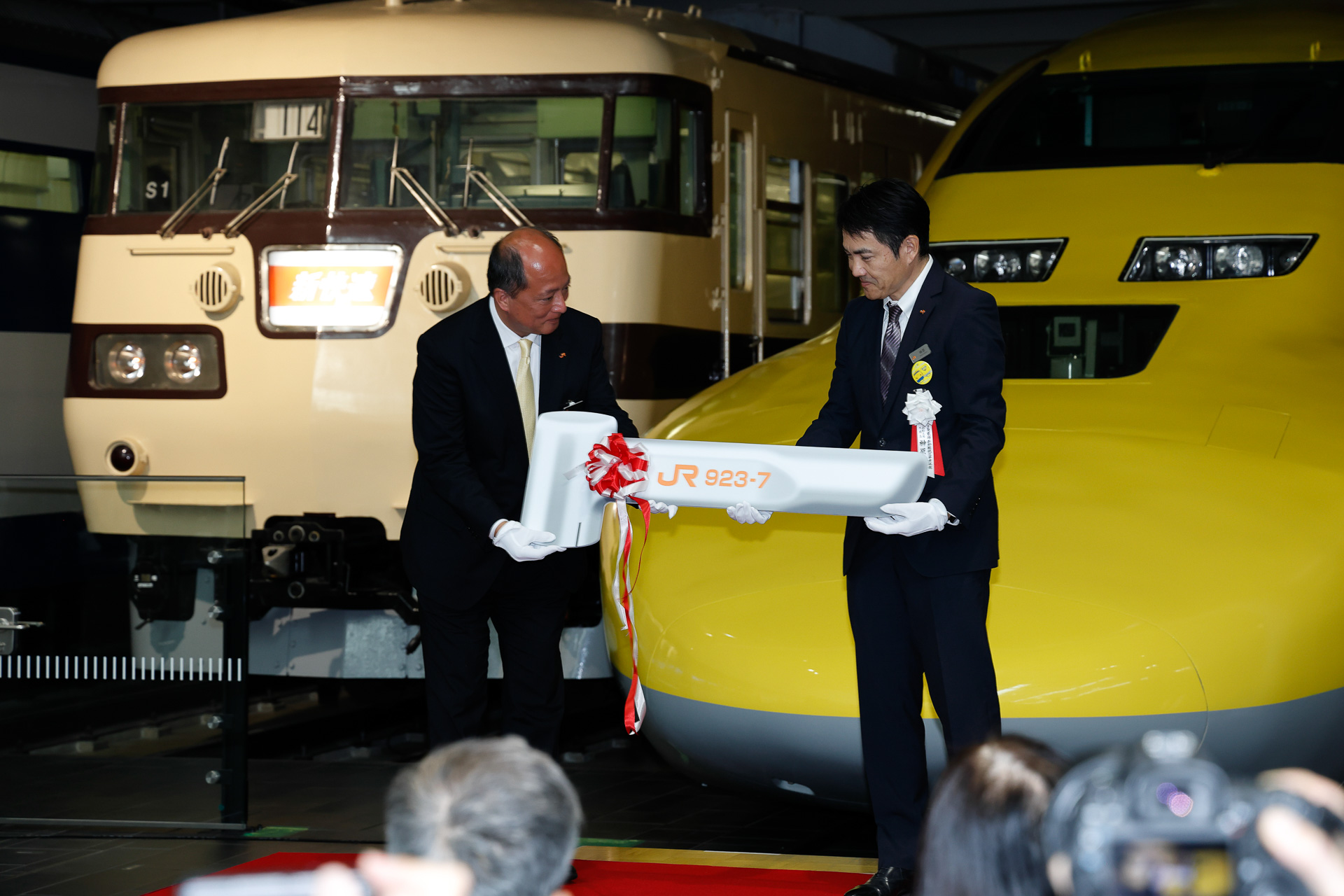 榊原工場長から岡部館長に、引き渡しの象徴として「ブレーキハンドル」をかたどったプレートが渡された