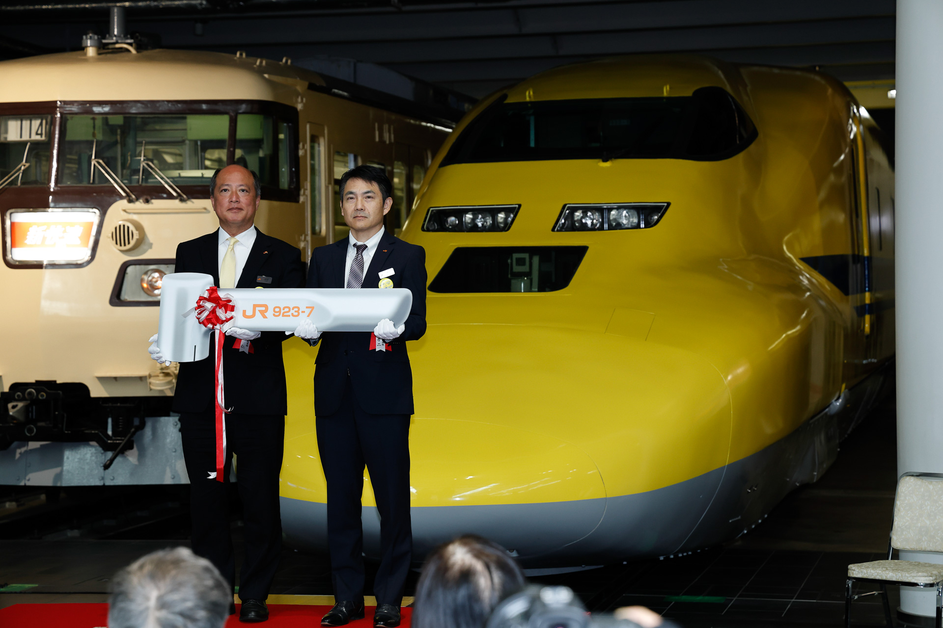 そのプレートを2人で持って記念撮影。ちなみに、本物の新幹線電車のブレーキハンドルは固定されていて外すことはできないが、古い在来線車両ではブレーキハンドルが着脱可能で、使用するときだけ取り付けるのが一般的