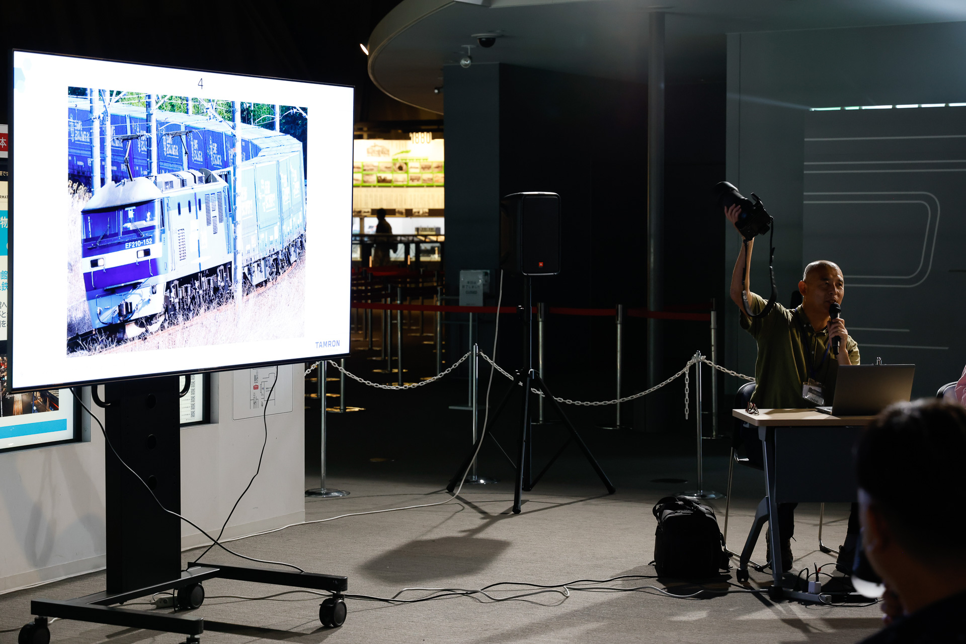 右手で機材の現物を示しながら、望遠レンズを使った作例について語る金盛氏