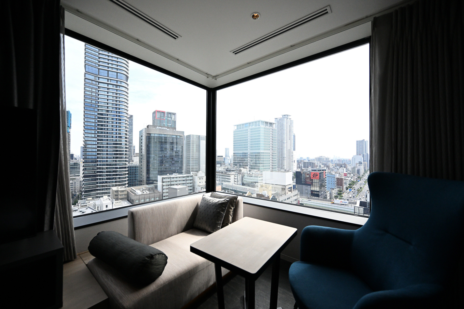 大阪の景色を見渡す大きな二面窓のジュニアスイート。大きなソファや椅子でくつろぎながらゆったりとした時間を過ごすことができる