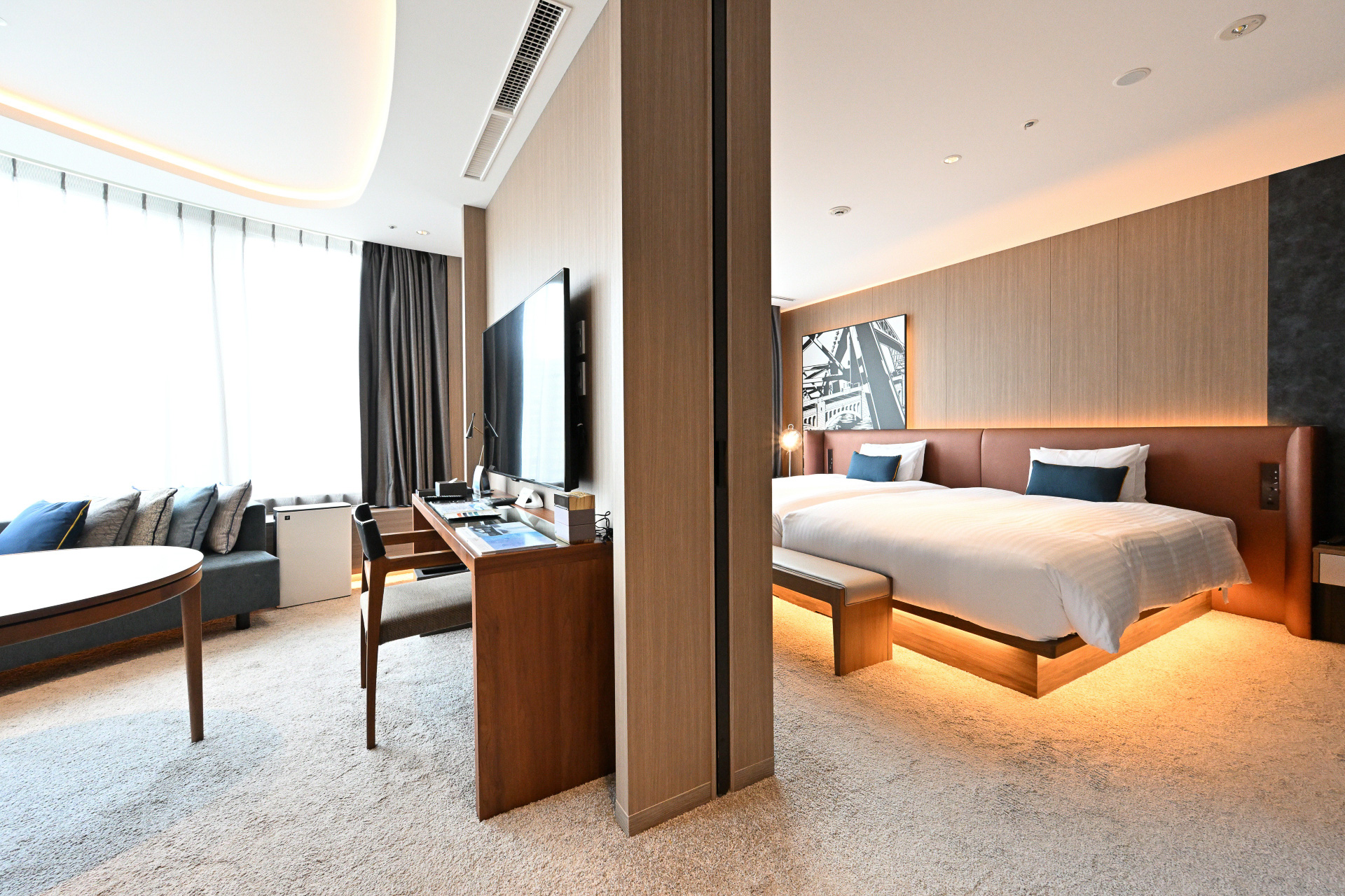 ホテルインターゲート大阪 梅田のフラグシップルーム、「インターゲートスイート」。アール形状の大きな窓を備え、大阪の景色を望むリビングルーム。そして仕切られたベッドルームは我が家のようにくつろぐことができる