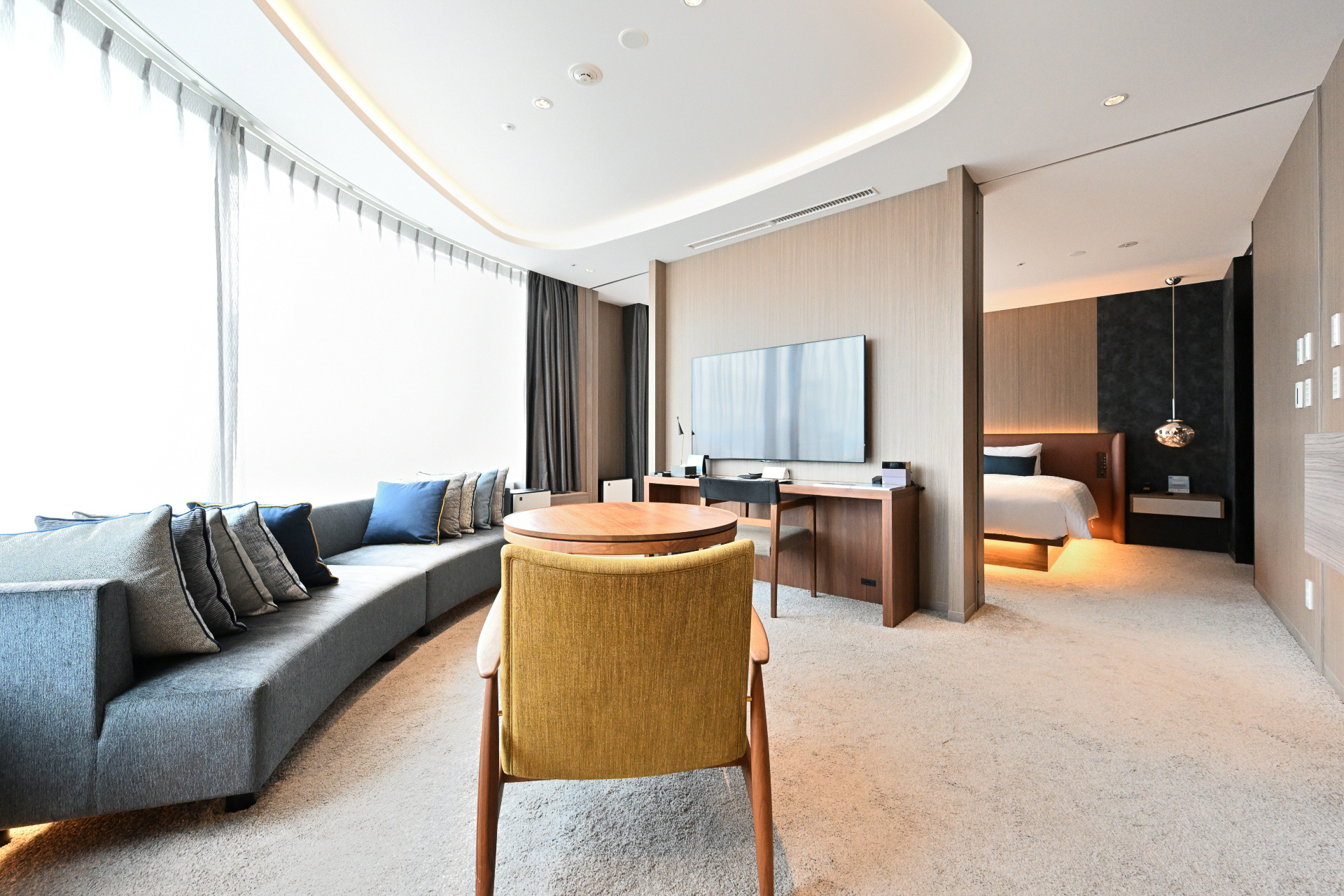 ホテルインターゲート大阪 梅田のフラグシップルーム、「インターゲートスイート」。アール形状の大きな窓を備え、大阪の景色を望むリビングルーム。そして仕切られたベッドルームは我が家のようにくつろぐことができる