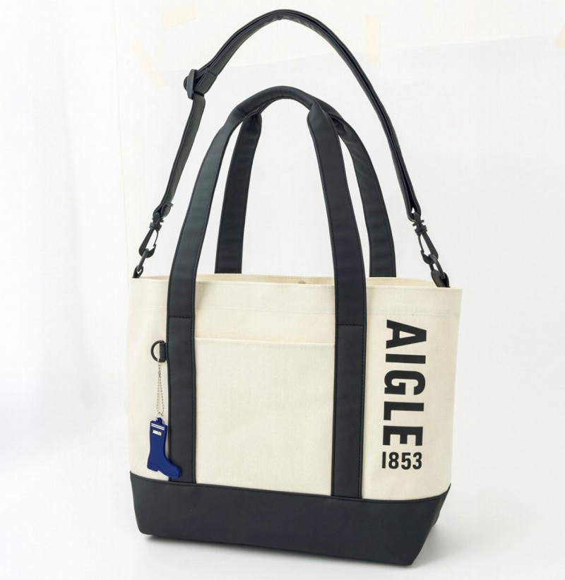 ラバーブーツを思わせる帆布調とラバー調の異素材を組み合わせたトートバッグ「AIGLE TOWN⇔OUTDOOR TOTE BAG BOOK」。サイズは約34～48×15×32cm（幅×奥行き×高さ）、取り外し可能なショルダーストラップの長さ115cm、チャームは青