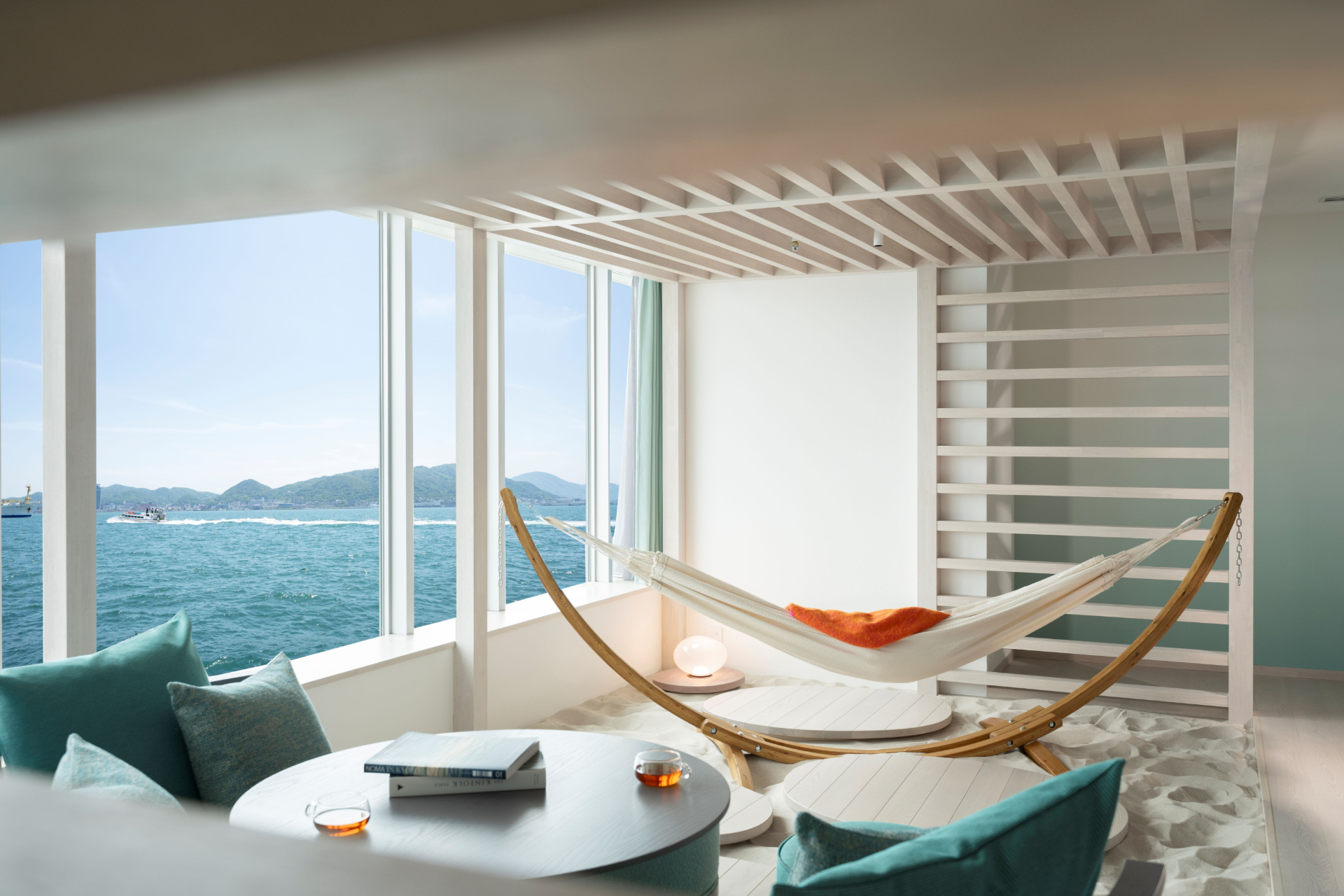 リゾートの浜辺をイメージし、砂浜を敷き詰めたリビングにハンモックやソファを設置する「海峡カバナスイート」