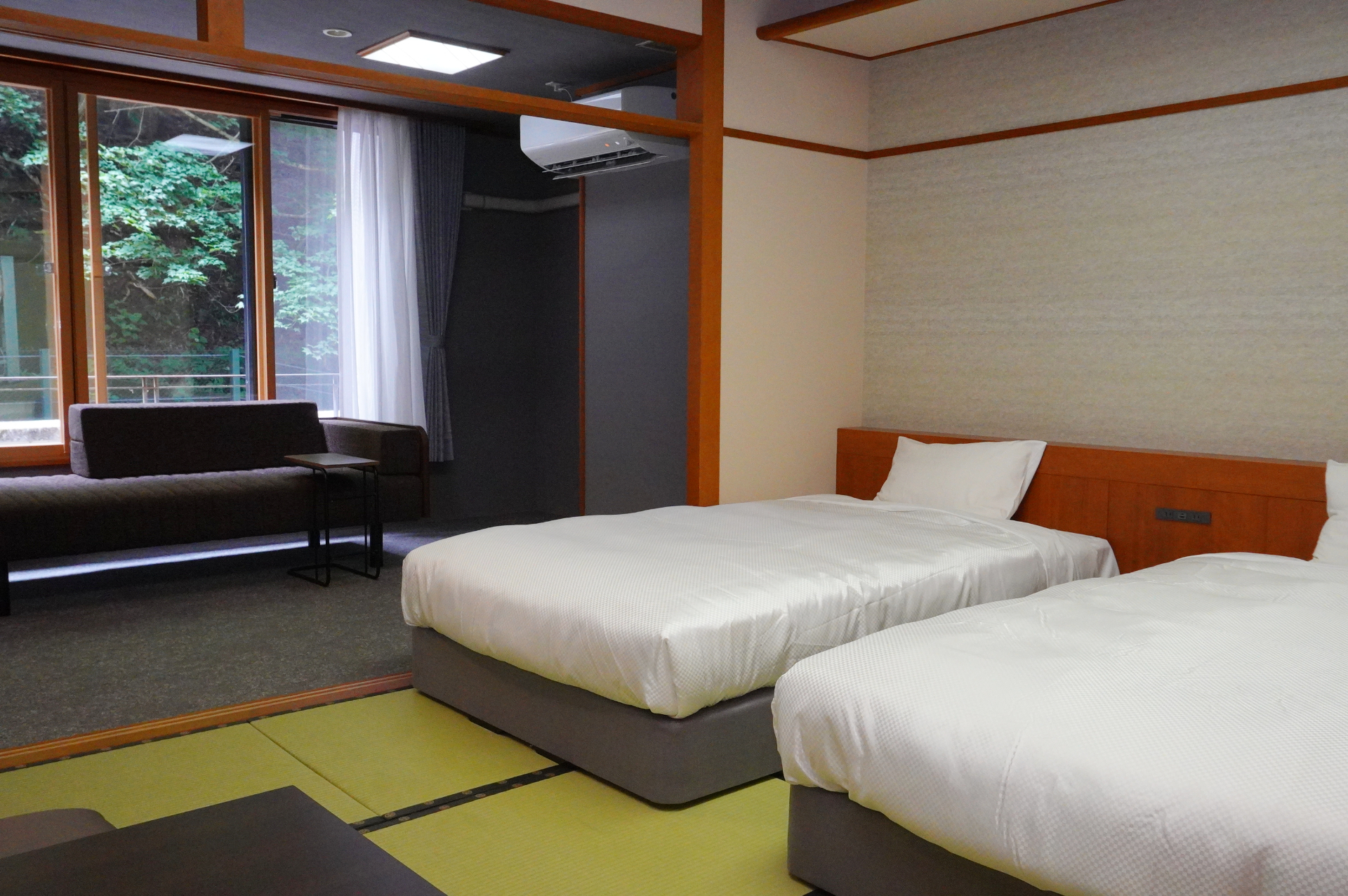 写真は#302「スタンダード和ベッドツイン10.5畳＋4.5畳」（定員6名、約51.9m<span class="em sup">2</span>）。ベッド枕元に電源コンセントを配置しているのもありがたい