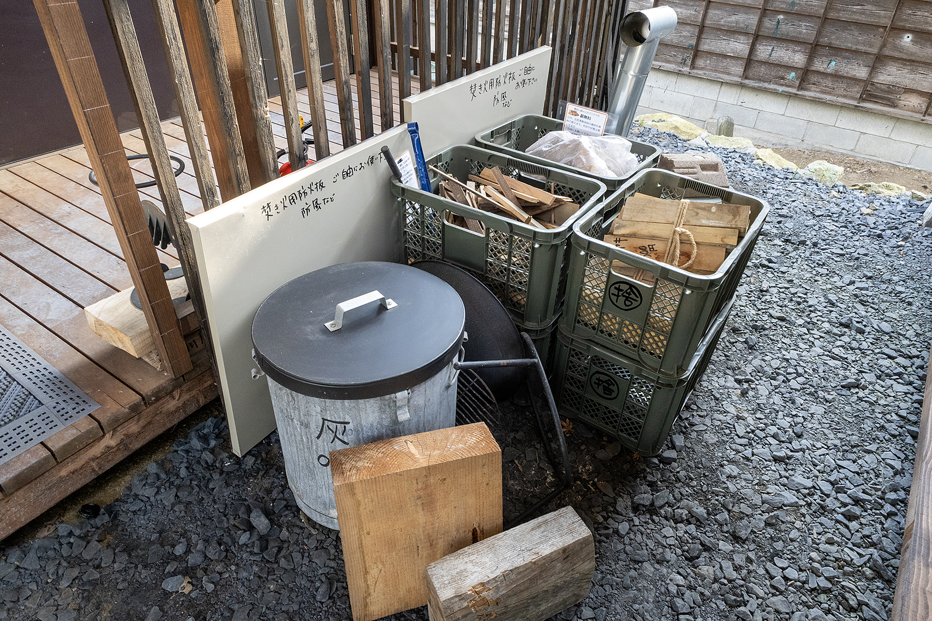薪置き場。薪の種類は主に建築物の解体で出た木材で販売している。たき火台や隣のサイトに爆ぜや煙が行かないよう配慮するための防火板は無料でレンタルしている