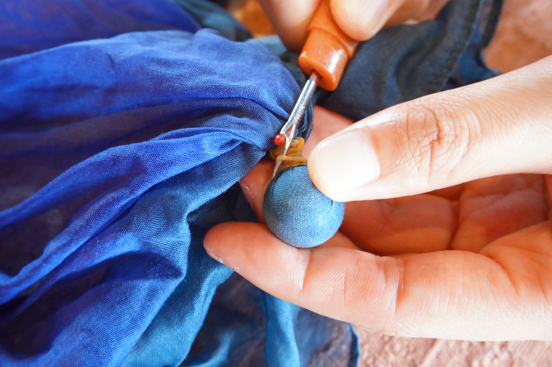 全体をきつく棒に巻きつけ、高温の温泉水で洗う→乾燥を数回繰り返すことで“色抜き”します。縛った部分をほどくと模様が現われ、最後にアイロンをかけて完成