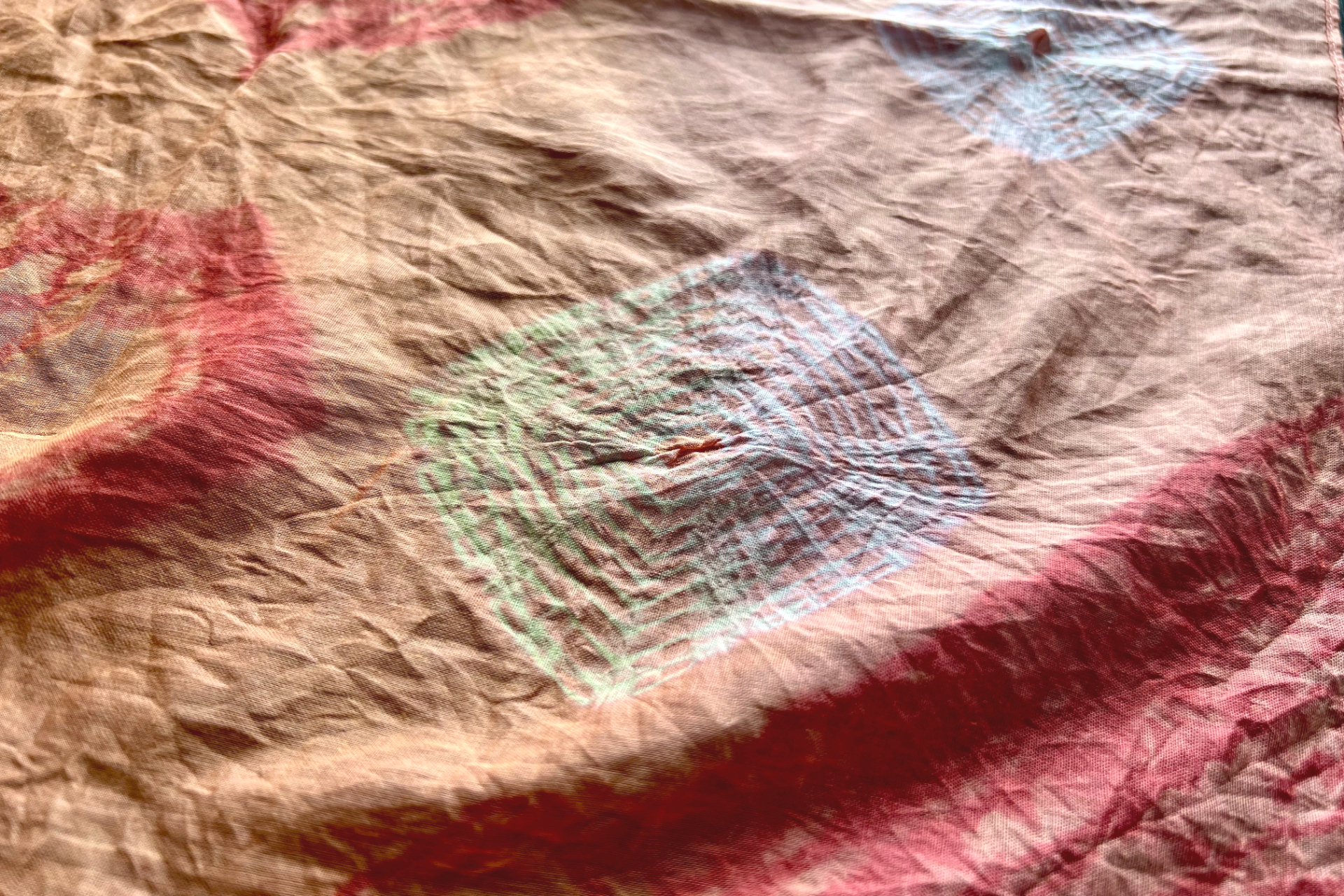 全体をきつく棒に巻きつけ、高温の温泉水で洗う→乾燥を数回繰り返すことで“色抜き”します。縛った部分をほどくと模様が現われ、最後にアイロンをかけて完成