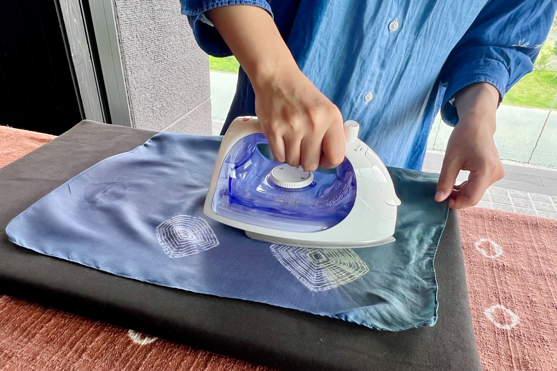 全体をきつく棒に巻きつけ、高温の温泉水で洗う→乾燥を数回繰り返すことで“色抜き”します。縛った部分をほどくと模様が現われ、最後にアイロンをかけて完成