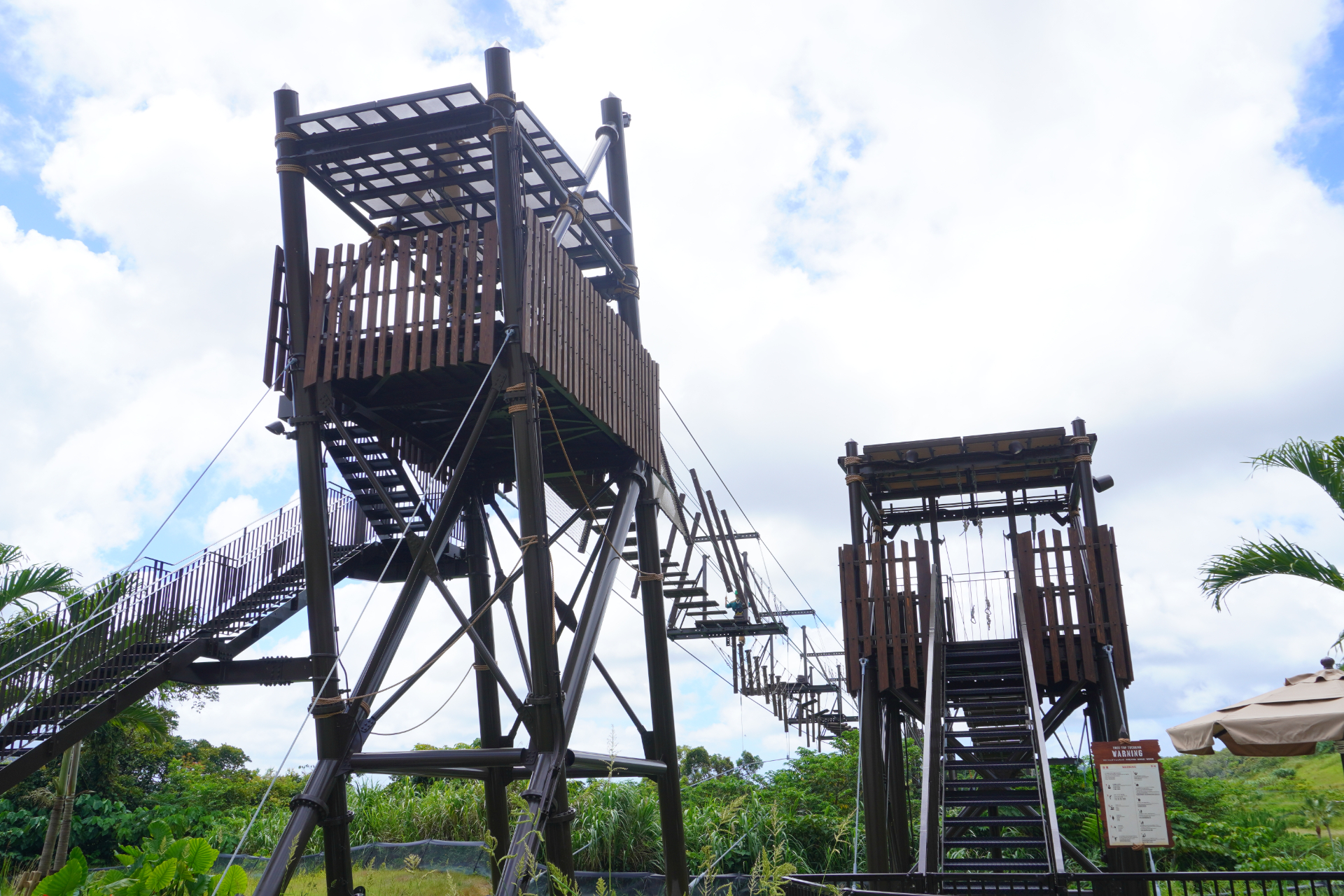 「スカイエンドトレッキング」はロープを頼りに空の上を歩く全長84mの難関アスレチック。不安定な踏み板の真下はジャングルの谷底でスリル満点。体験前には、ナビゲーターがしっかりと命綱を装着してくれる
