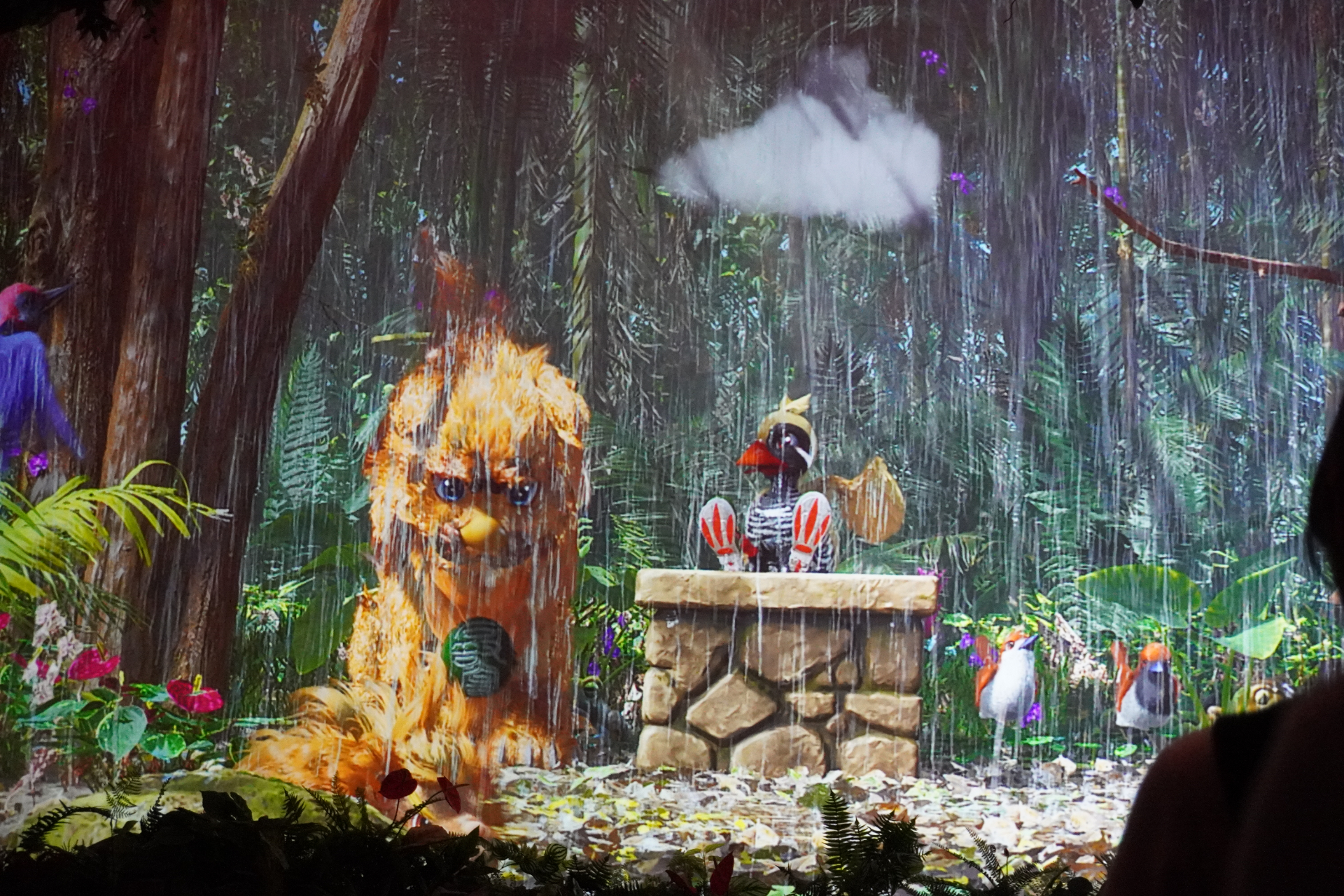 屋内シアター型アトラクション「やんばるフレンズ」。プレショーでは研究所のような空間でやんばるの森の生態について学びつつ、動くはずのない絵が生き物のようにはしゃぎだし……。メインシアターへ移動すると、ヤンバルクイナの「ジャン」と守り神のシーサー「シン」が登場し、ゲストとの会話や問答を繰り広げる。突然雨が振り出して濡れちゃうかも？