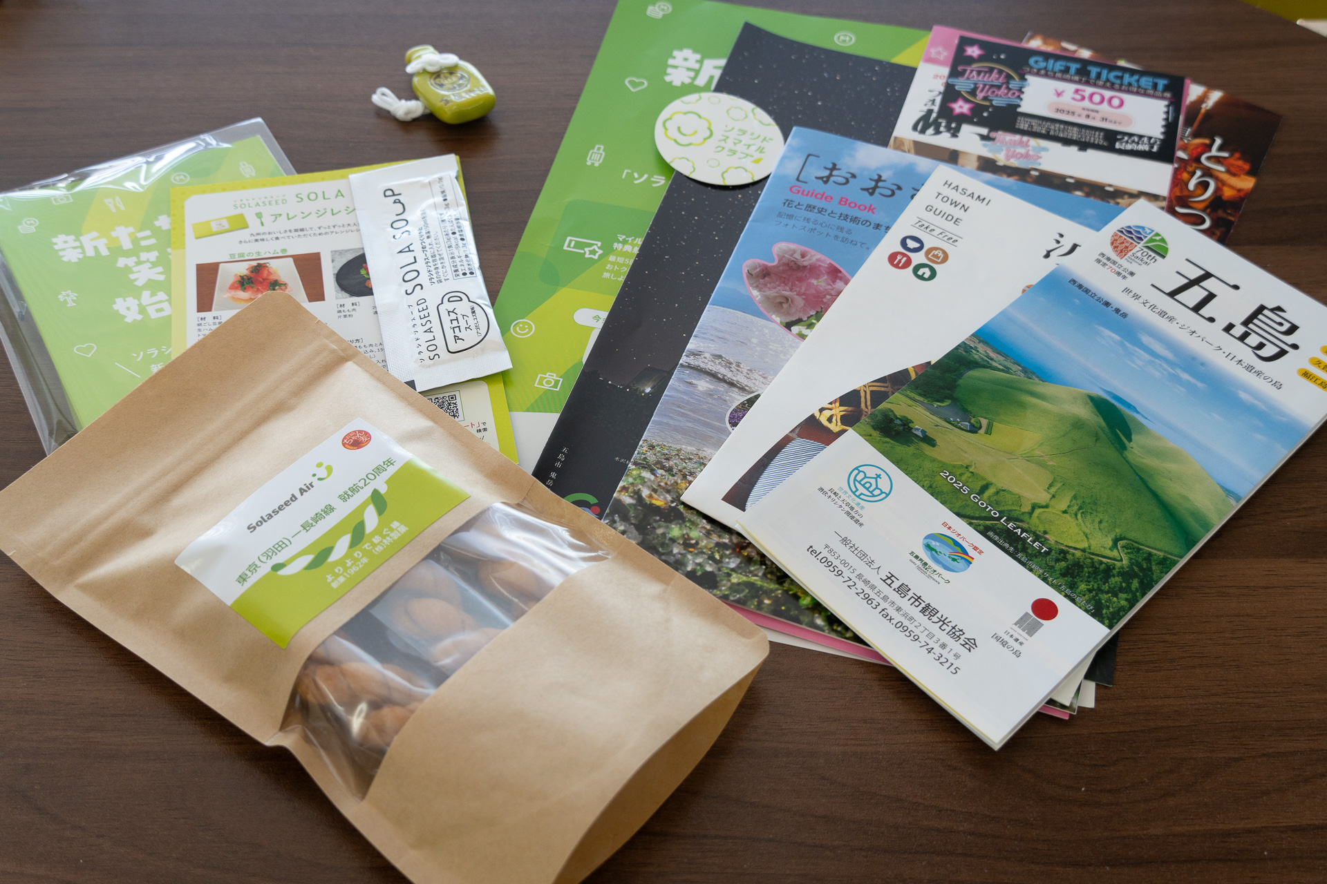 波佐見町「金屋神社」の波佐見焼のお守り（左上）やソラシドエアロゴ入りの長崎銘菓「よりより」（左下）、連携協定締結自治体の観光案内、ソラシド ソラスープなどを詰め合わせた記念品