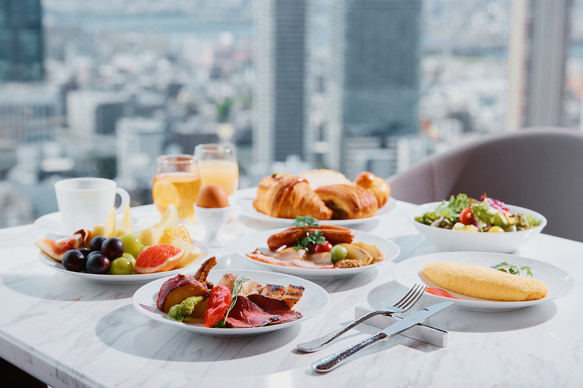 翌朝食ビュッフェでは、国産牛の炭火焼、毎朝焼き上げる自家製パン、マスクメロンをはじめとした季節の果物などをラインアップ