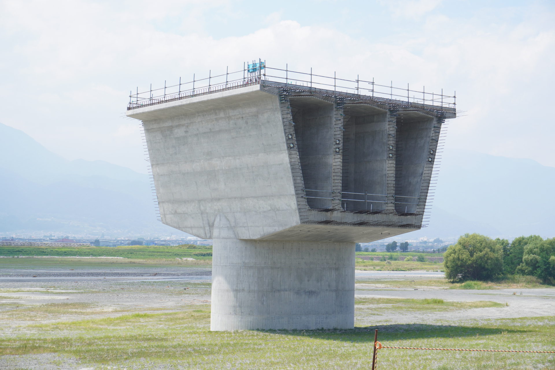新設される山梨県駅からは西へ5kmほどの地点にある。橋を支えるためのケーソン基礎や柱の部分（下部工）は完成しており、現在は桁（上部工）をつなげていくコンクリート打設作業などを行なっている