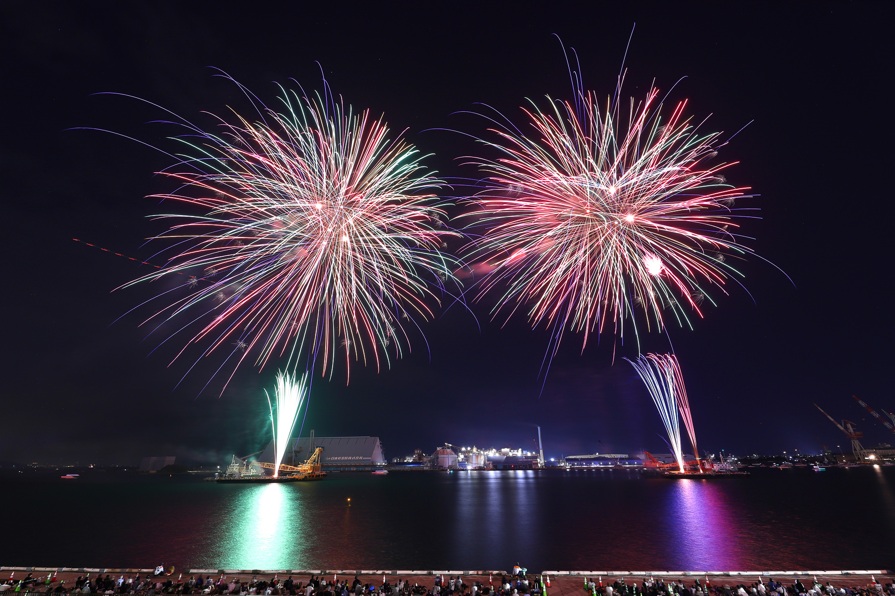 2隻の台船からテンポよく花火が上がる。空に浮かぶ赤い軌跡はヘリコプターの航空灯