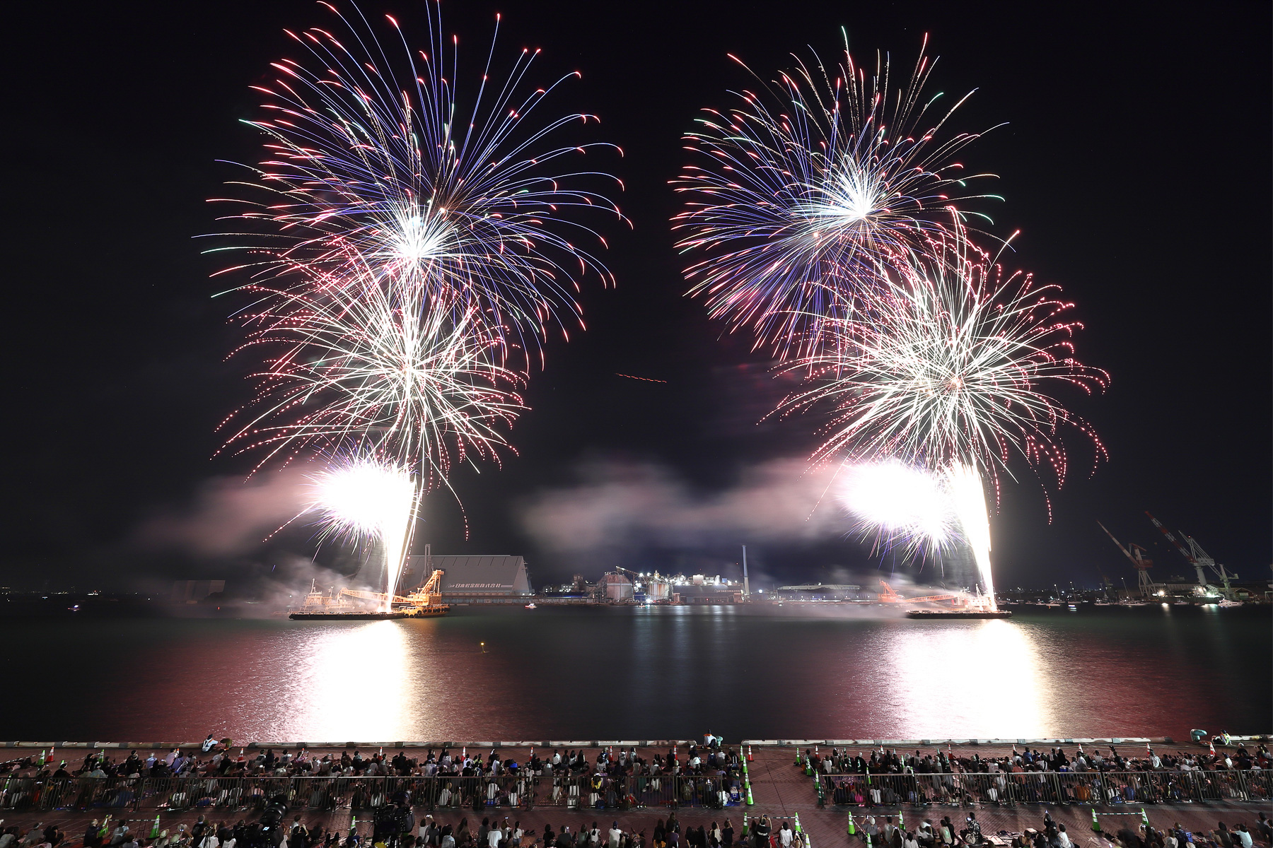 2隻の台船からテンポよく花火が上がる。空に浮かぶ赤い軌跡はヘリコプターの航空灯