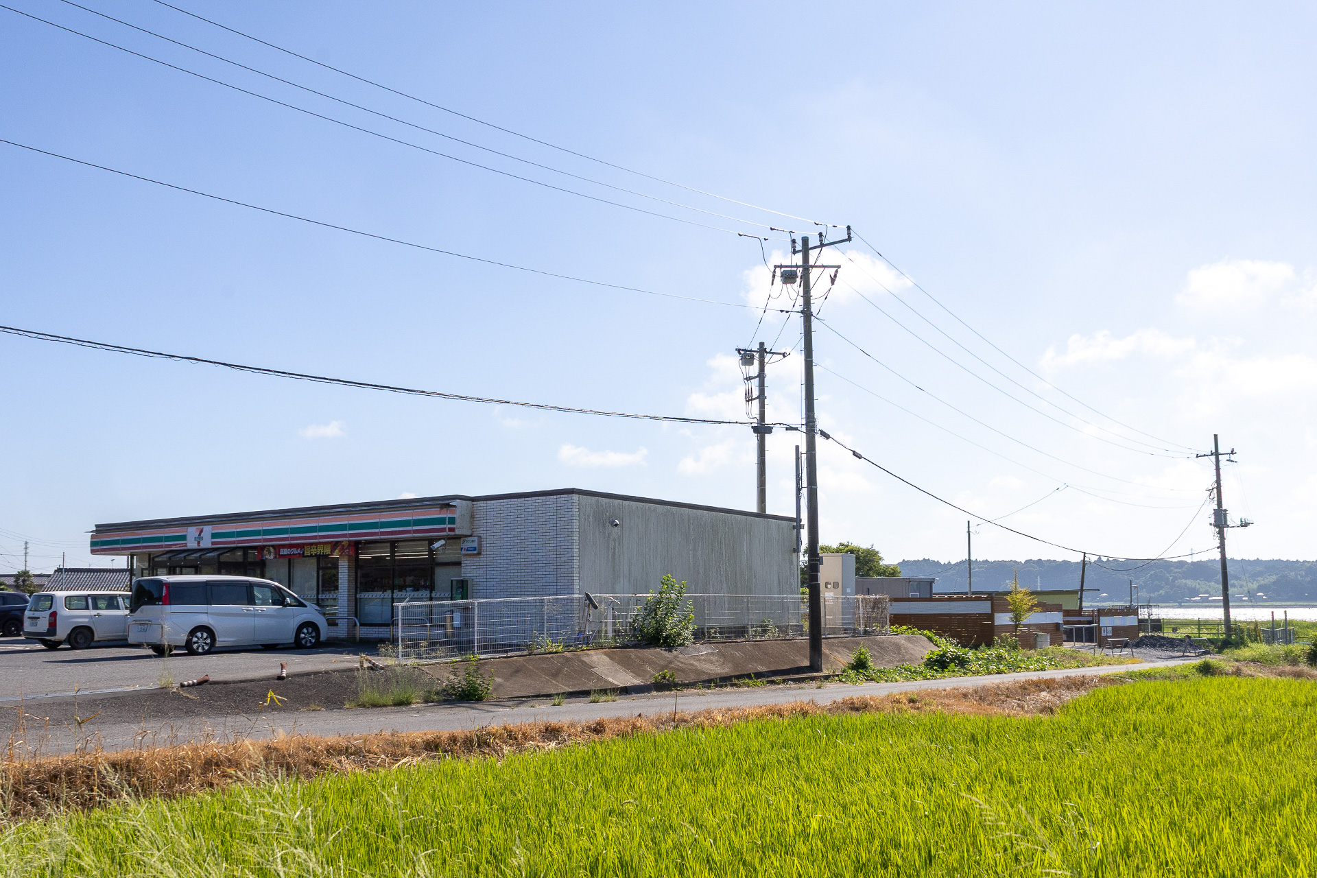 スーパーまで必要ないという場合はかなり楽。なんと施設の隣はセブン-イレブン。写真の手前がコンビニで、奥に北浦レイクサイドRVパークが見える。お弁当を買って温めてもらっても冷めることない距離だ