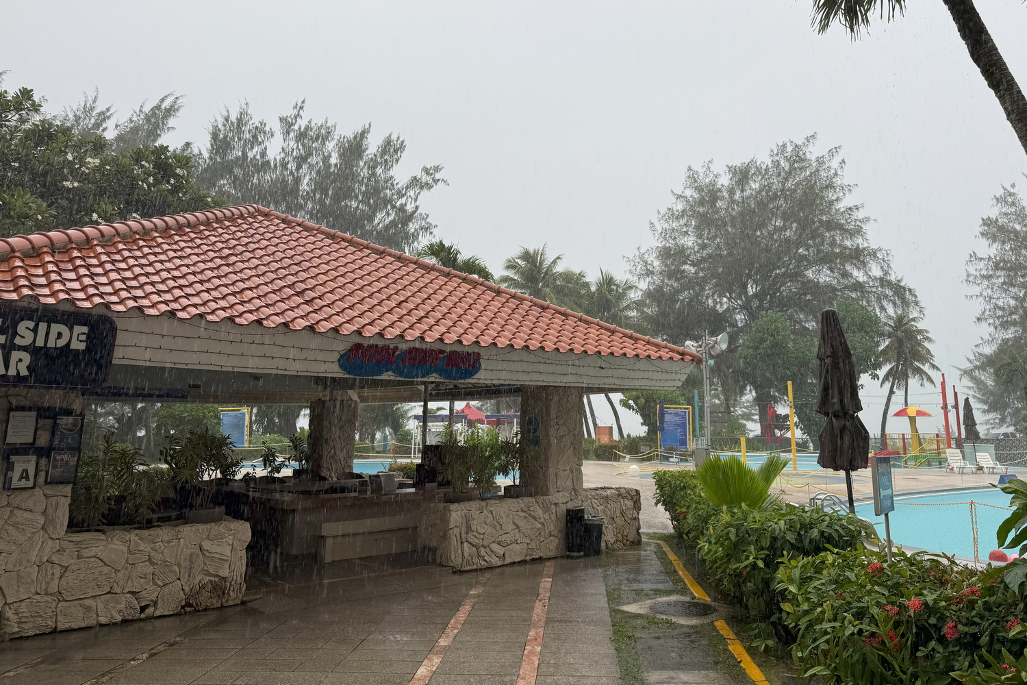 プールの脇にある「プールサイドバー」（営業前）。撮影に立ち寄ったときはタイミングわるく土砂降りに……。この先にビーチがある