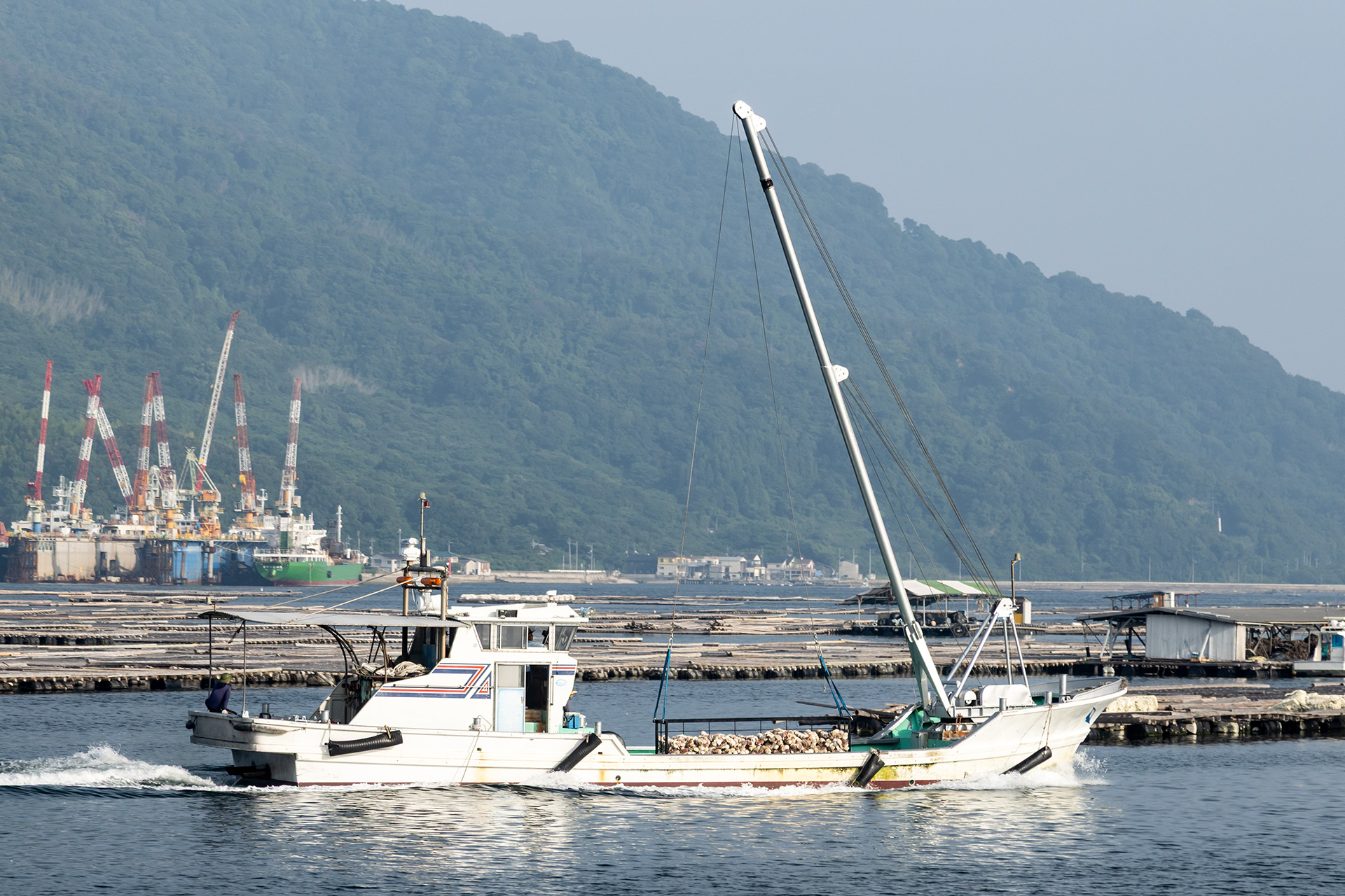 遠くには牡蠣筏とともにカキを積んだ漁船の姿