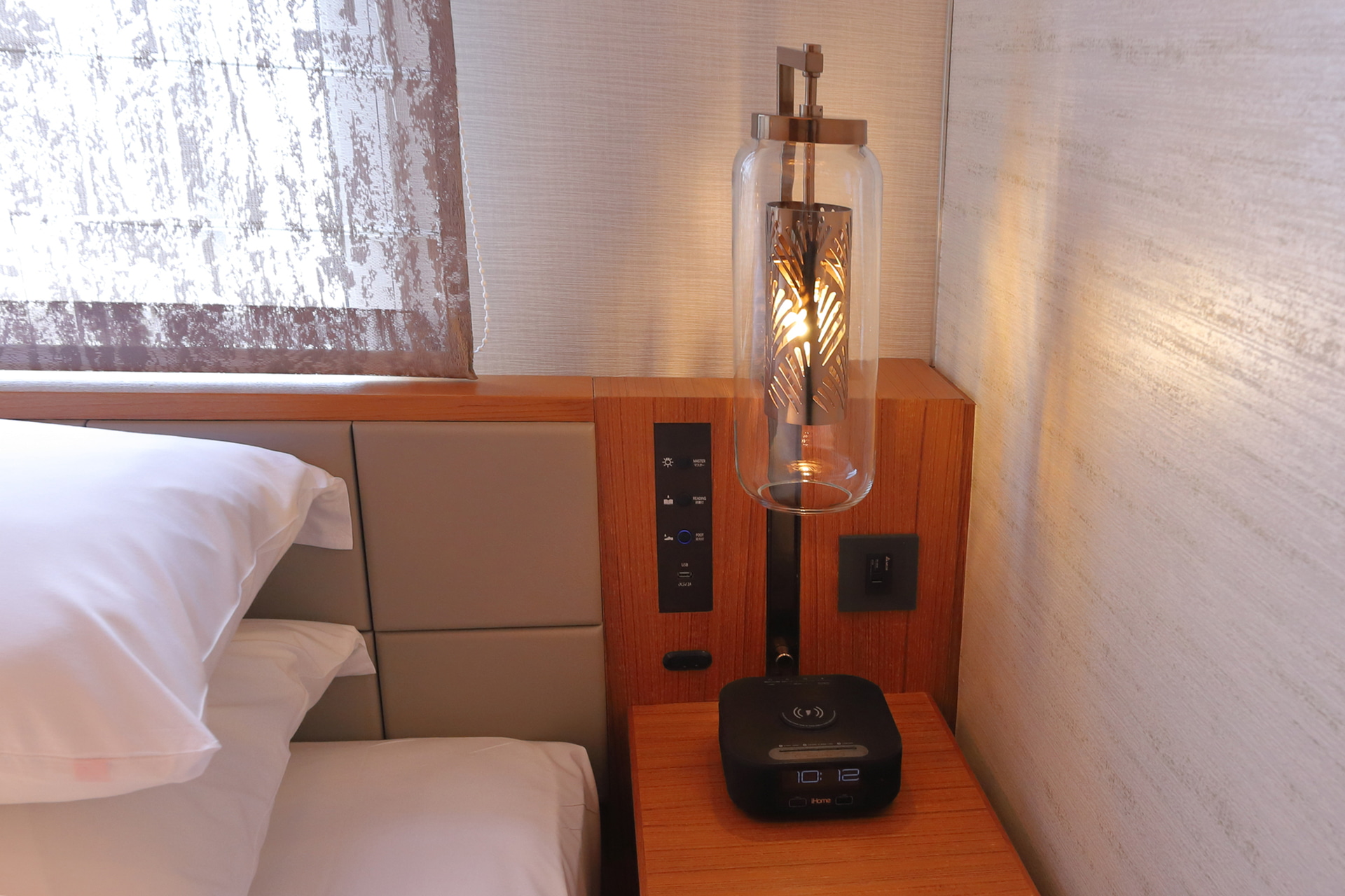 ベッドサイドのナイトテーブル。アラームクロック、充電用USBポート、客室照明のコントロールパネルがある