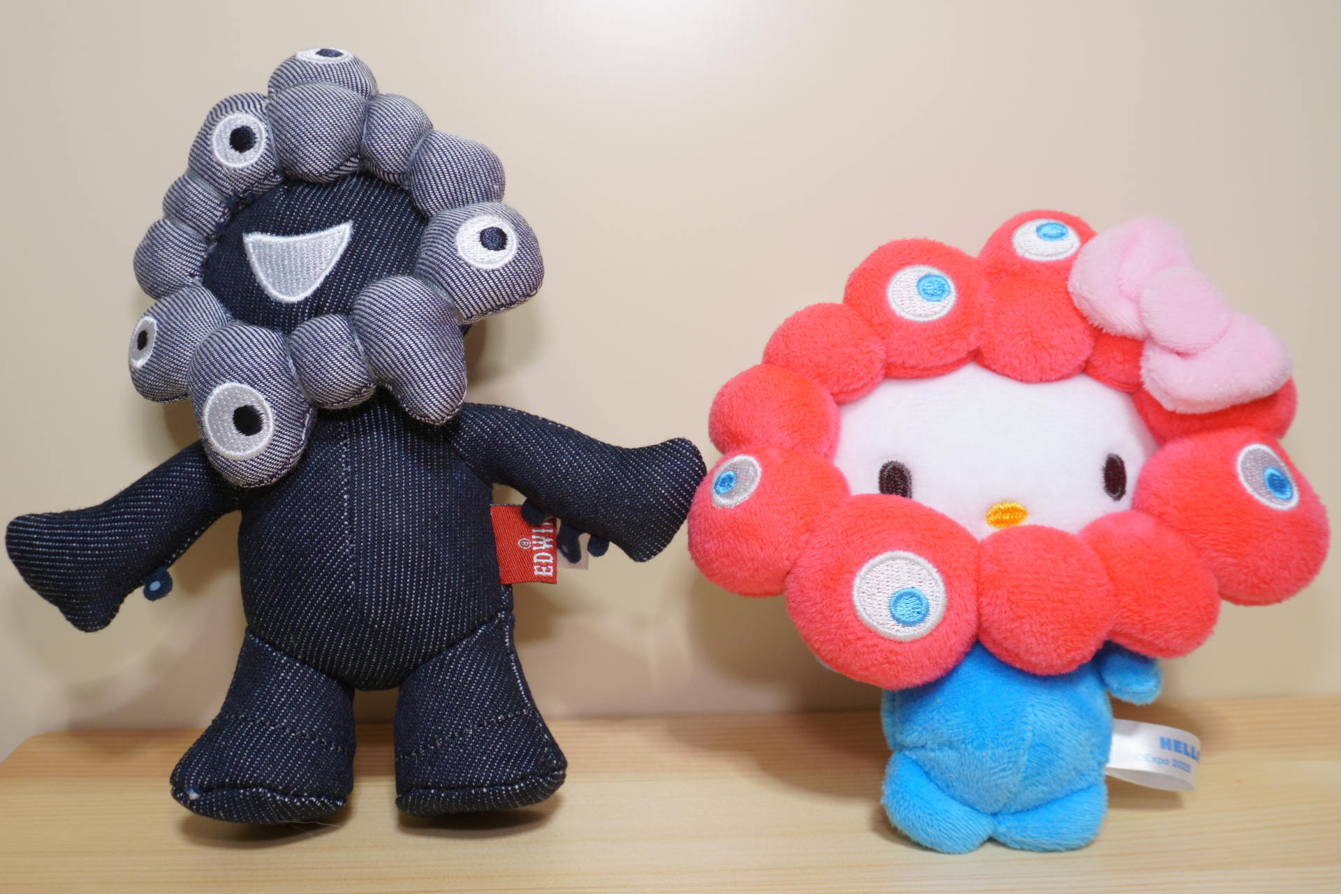 サンリオキャラクターズ ミャクミャクなりきりぬいぐるみBCカラー（キティ）を並べてみた様子。こちらは会場内限定カラーでやや入手難易度高めだが、ミャクミャク部分が赤い通常カラーは会場外の公式ストアやサンリオショップなどでも手に入る