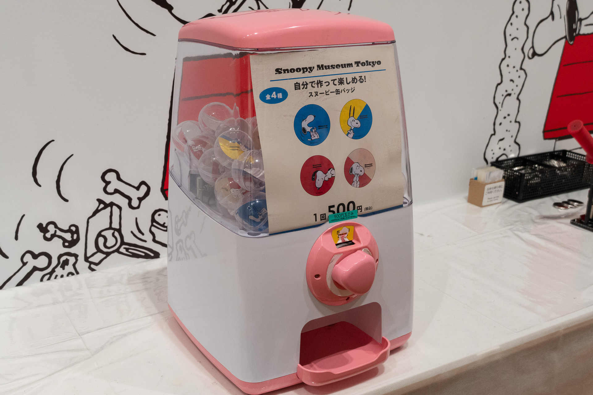 カプセルトイ自販機を回して出てきたランダムなデザインに、アルファベットシールを貼ってオリジナル缶バッジを制作できる「スヌーピー缶バッジ」（1回500円）は、ホログラム加工の新デザイン4種を追加（計10種に）