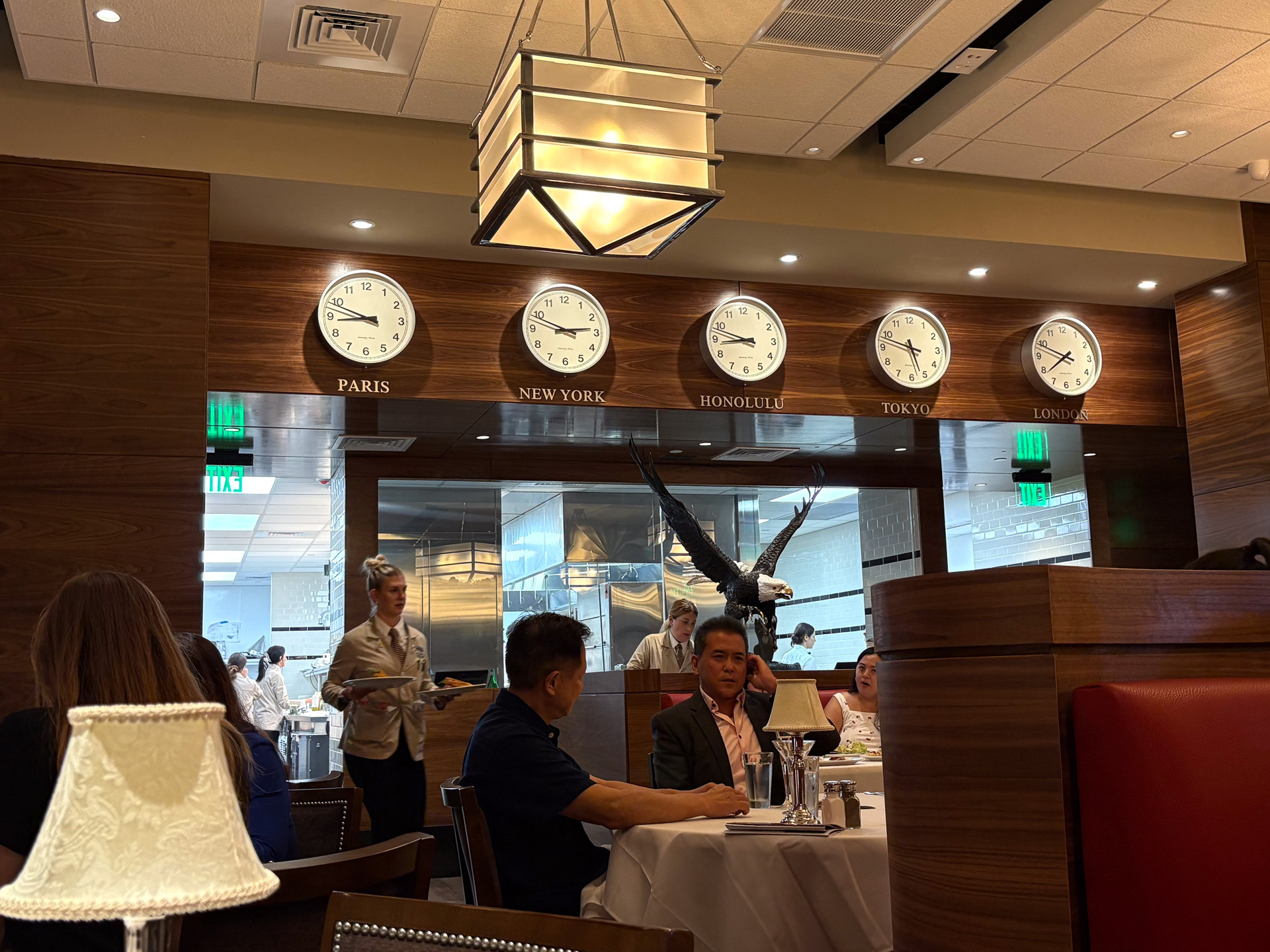 テーブル席、ソファ席の向こうにガラスで仕切られた広大なキッチンが備えられ、次々と料理が運ばれる