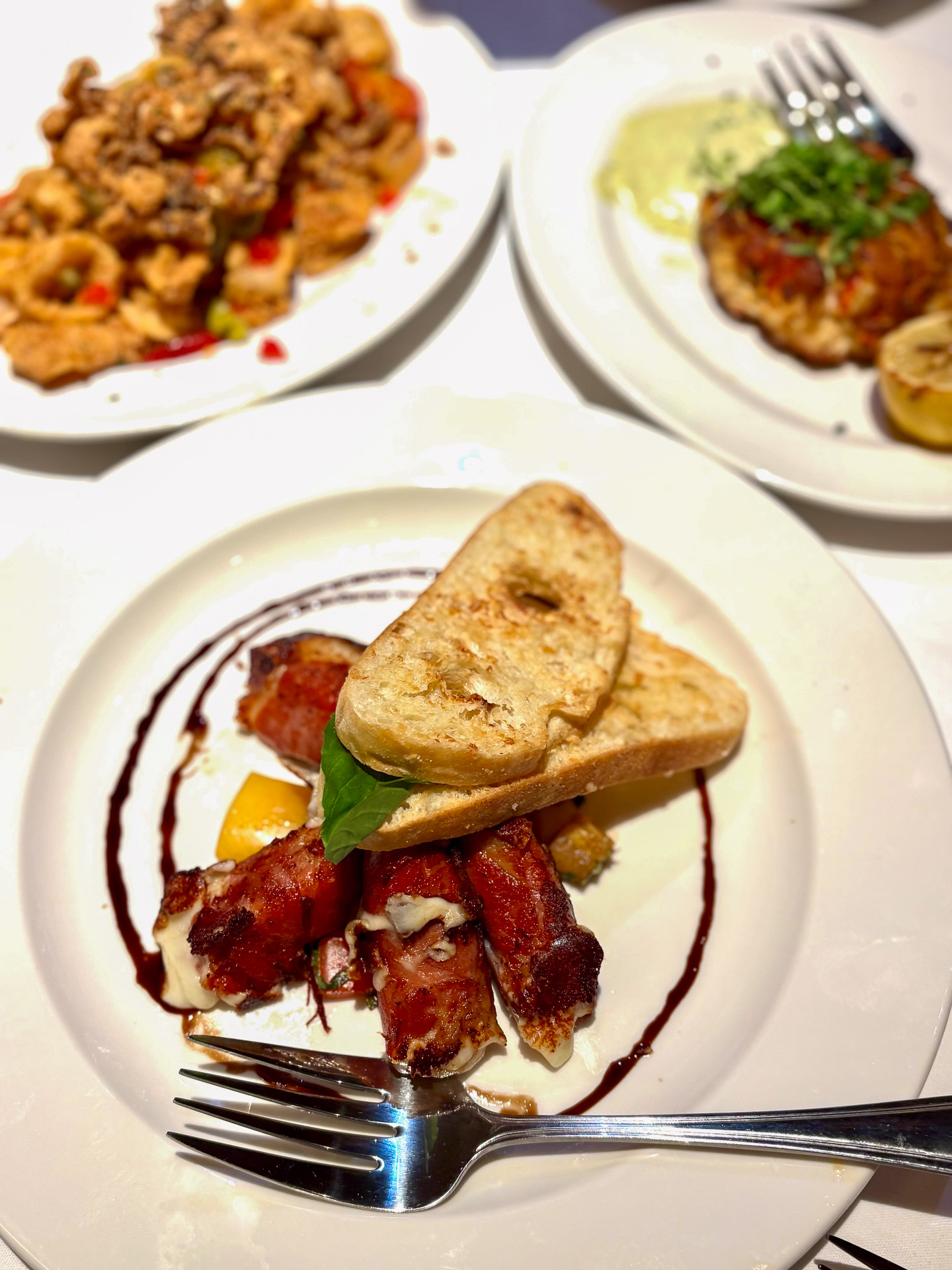 モッツァレラとプロシュート（22ドル）、左奥はチェリーペッパーを添えたカラマリのソテー（25ドル）