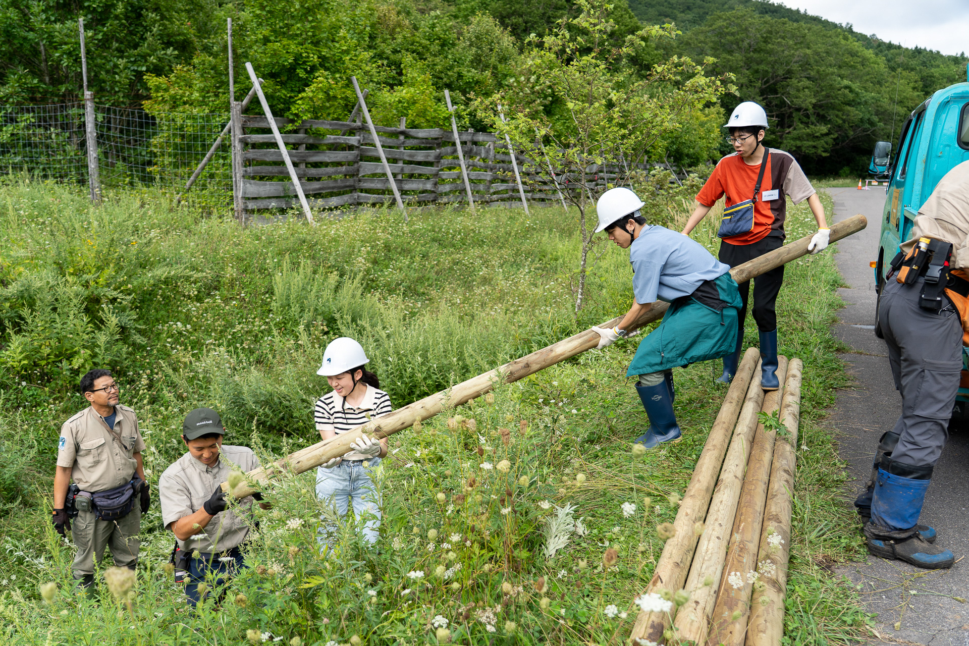 トラックから下ろした支柱を防鹿柵の近くまで運ぶ