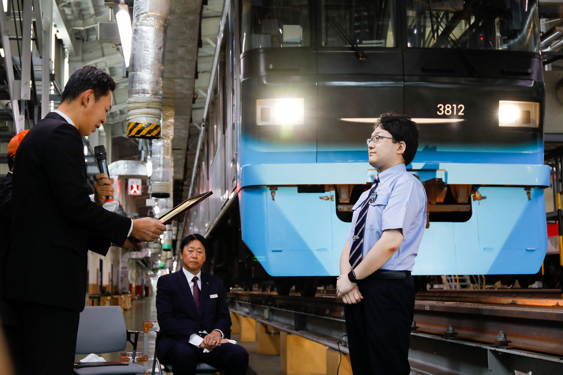 鉄道事業本部 車両部統括部長を務める門田吉人氏から、嵯峨野氏に表彰状が手渡される