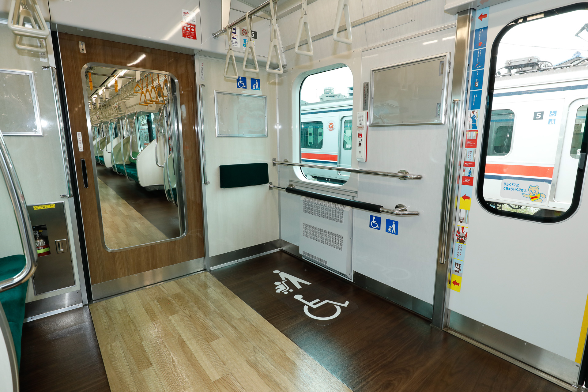 こちらは5号車車端部のフリースペース。床のピクトグラム標記や吊手の違いなど、仕様の相違が見て取れる