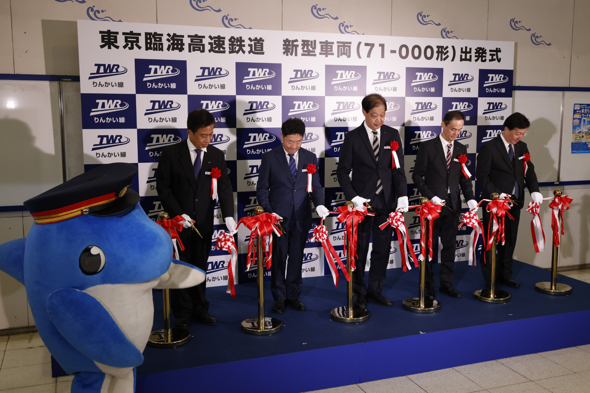 テープカット。左から順に、東京臨海高速鉄道株式会社 常勤監査役 上本敬氏、代表取締役専務 谷本俊哉氏、西倉社長、常務取締役 西尾佳章氏、運転・車両担当部長 高藤敏弘氏。そして左端には、りんかる