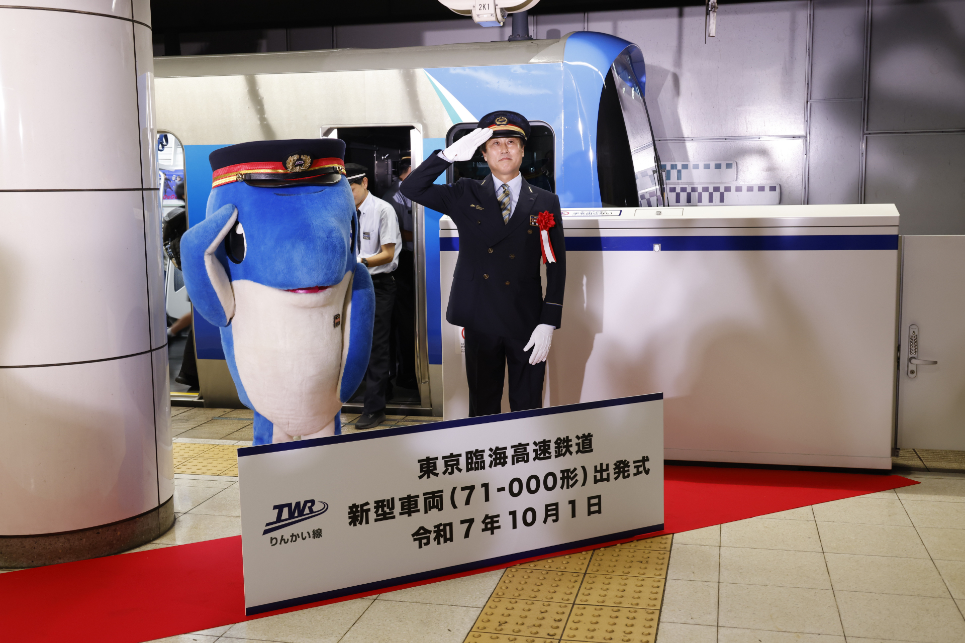 飯島管理駅長とりんかるが並んで、71-000形をバックにしてのフォトセッション